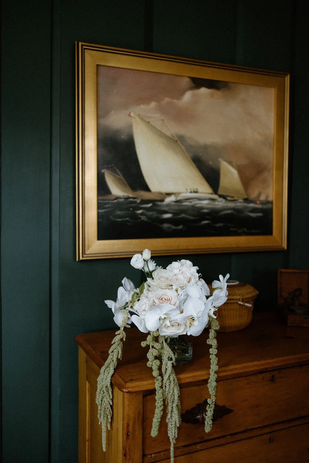 Airy white floral arrangement displayed beside framed artwork in a historic estate interior.