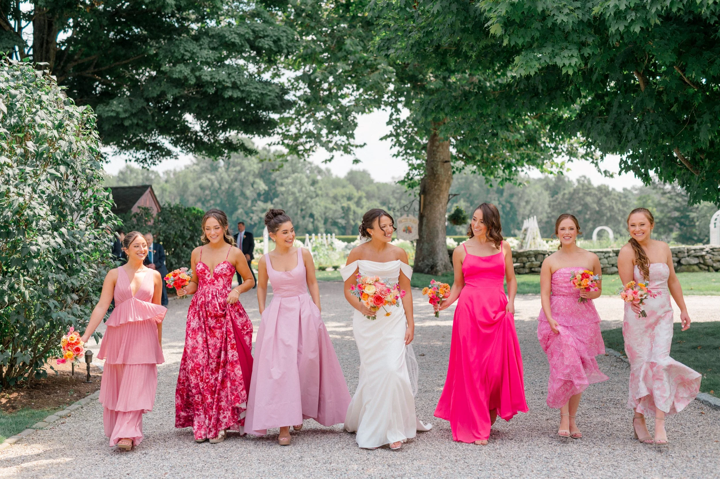 Bride in elegant off-the-shoulder gown holding vibrant summer bouquet.