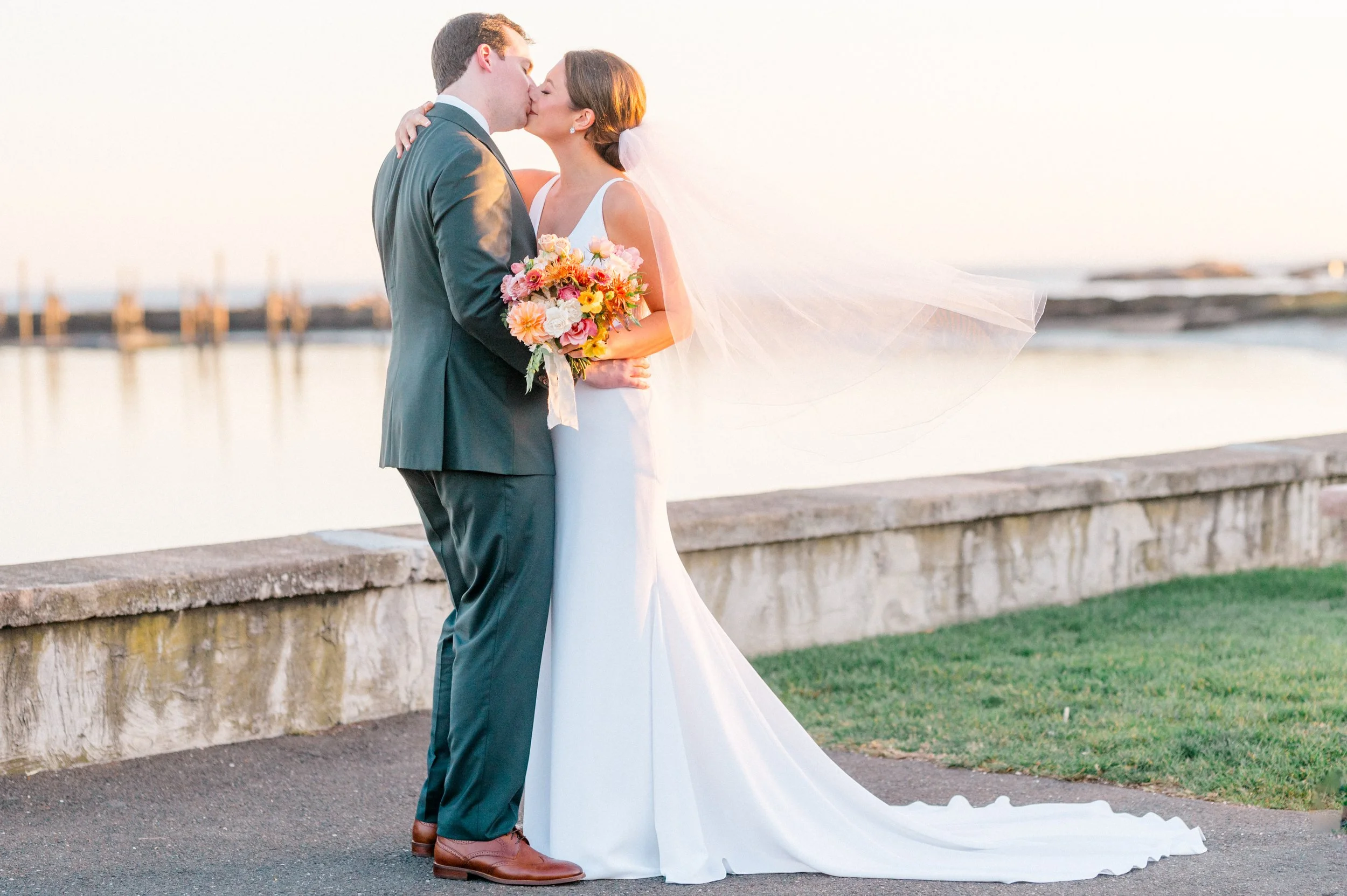 Bride and groom sharing a quiet moment by the water with her fall garden bouquet in focus.