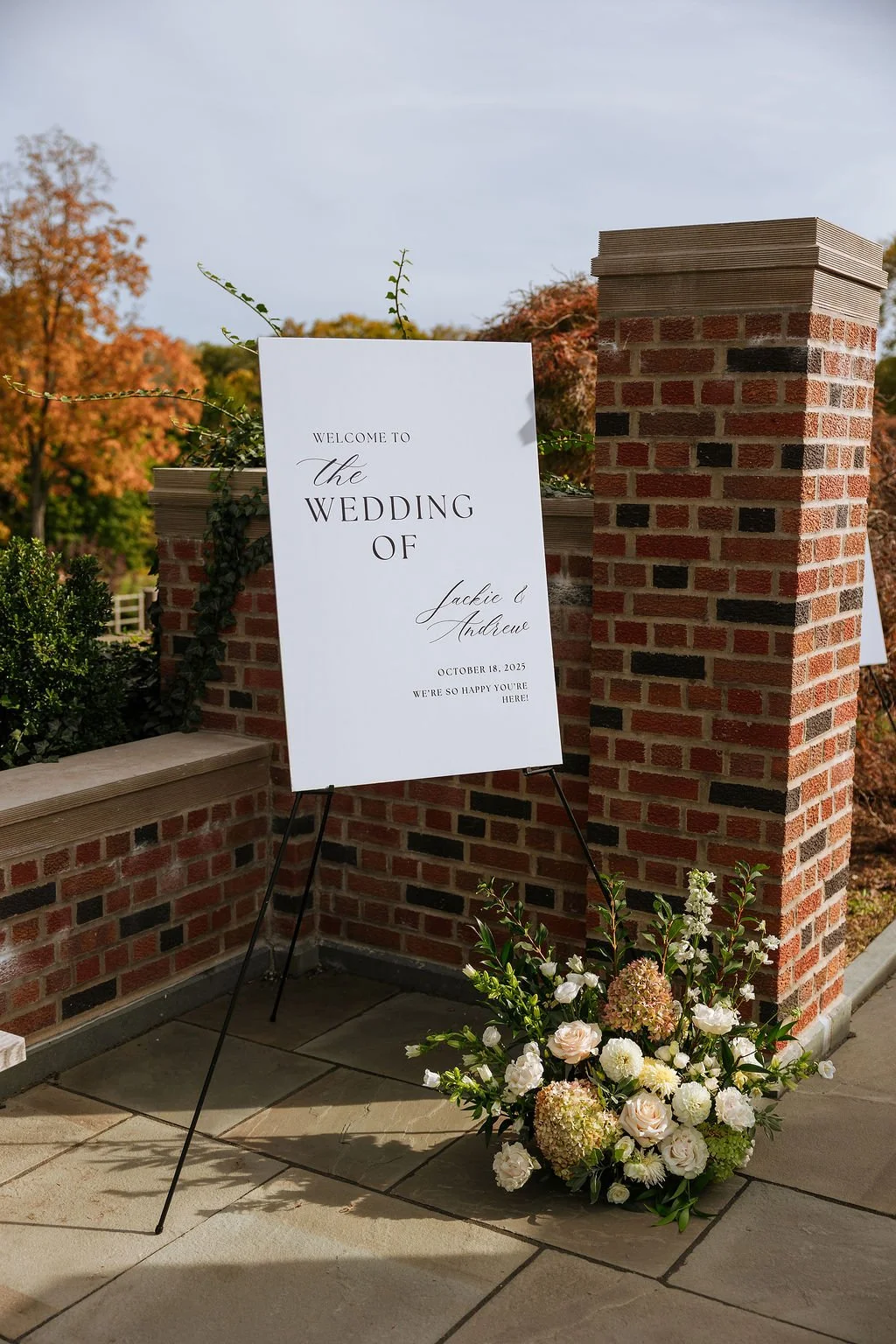 Neutral fall wedding ceremony flowers designed to complement client's welcome sign at historic garden setting