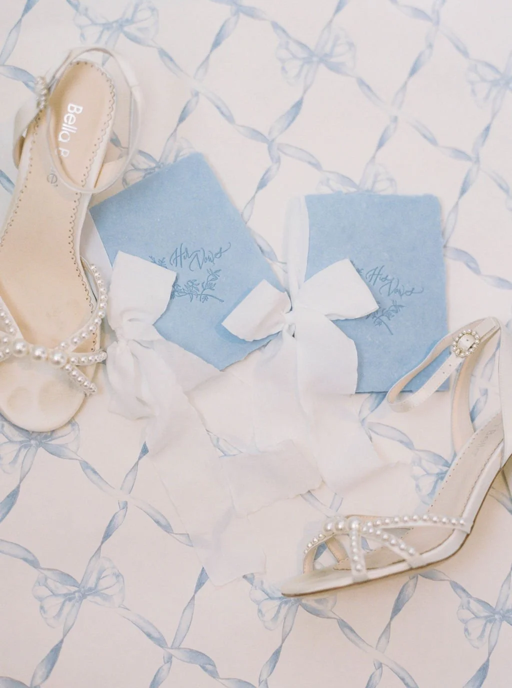 Elegant bridal shoes photographed with bouquet and soft blue stationery elements.