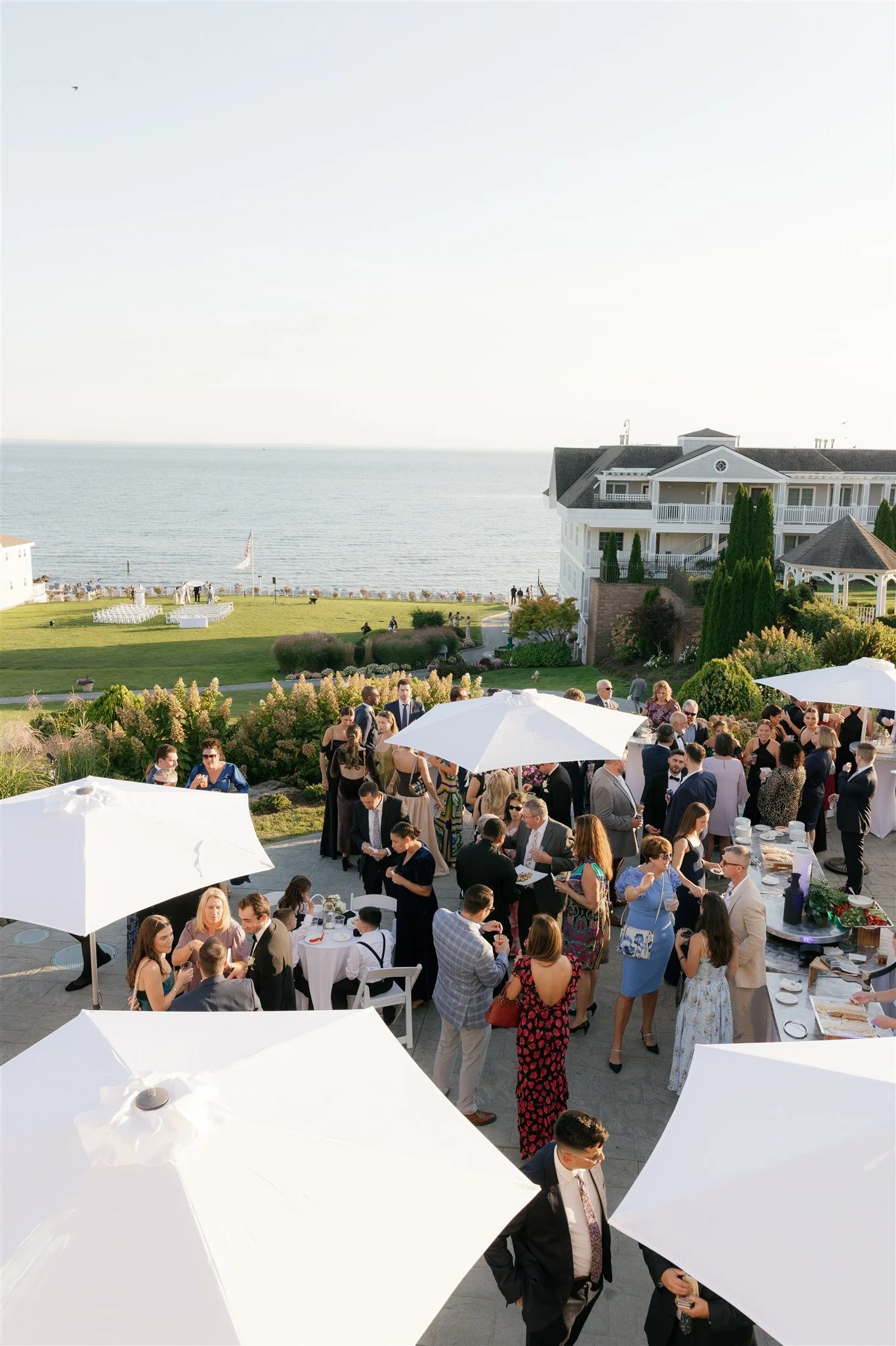 Overview of the coastal wedding reception featuring round tables, neutral linens, and soft white florals.
