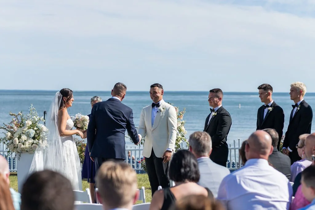 Waterfront wedding ceremony on the lawn at Water's Edge Resort and Spa in Westbrook Connecticut with white floral columns and Long Island Sound in the background