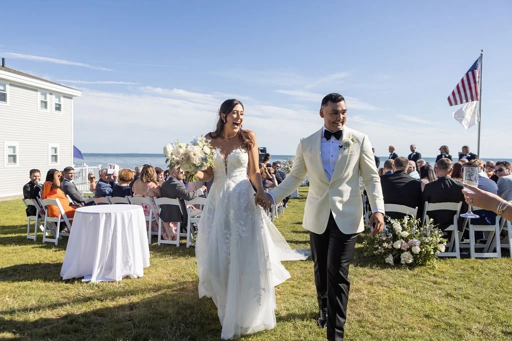 Wedding ceremony aisle view at Water's Edge Resort and Spa Westbrook Connecticut with garden floral arrangements and waterfront backdrop
