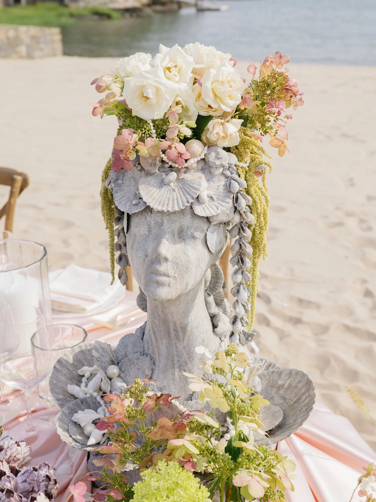 Close-up of sculptural bust draped in pearl strands amid hydrangea, shipwrecked gilded age design detail
