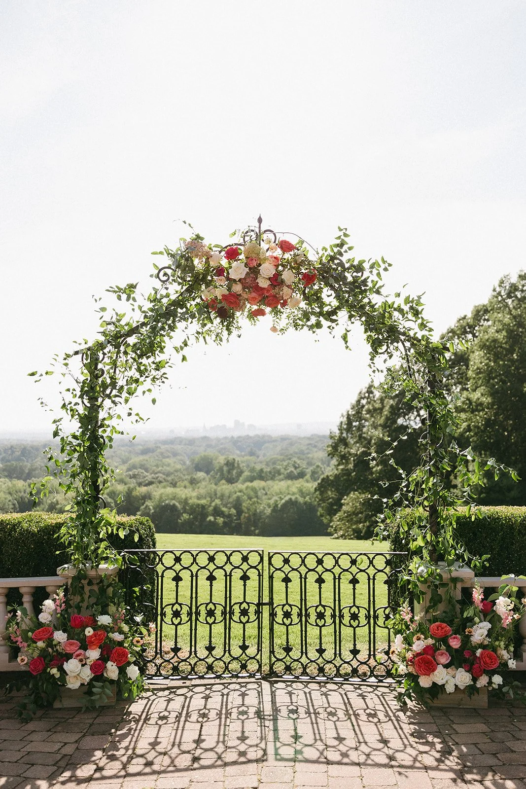 Garden wedding ceremony arch decorated with colorful pink, coral and ivory flowers by First Blush at Wickham Park in Manchester, Connecticut.