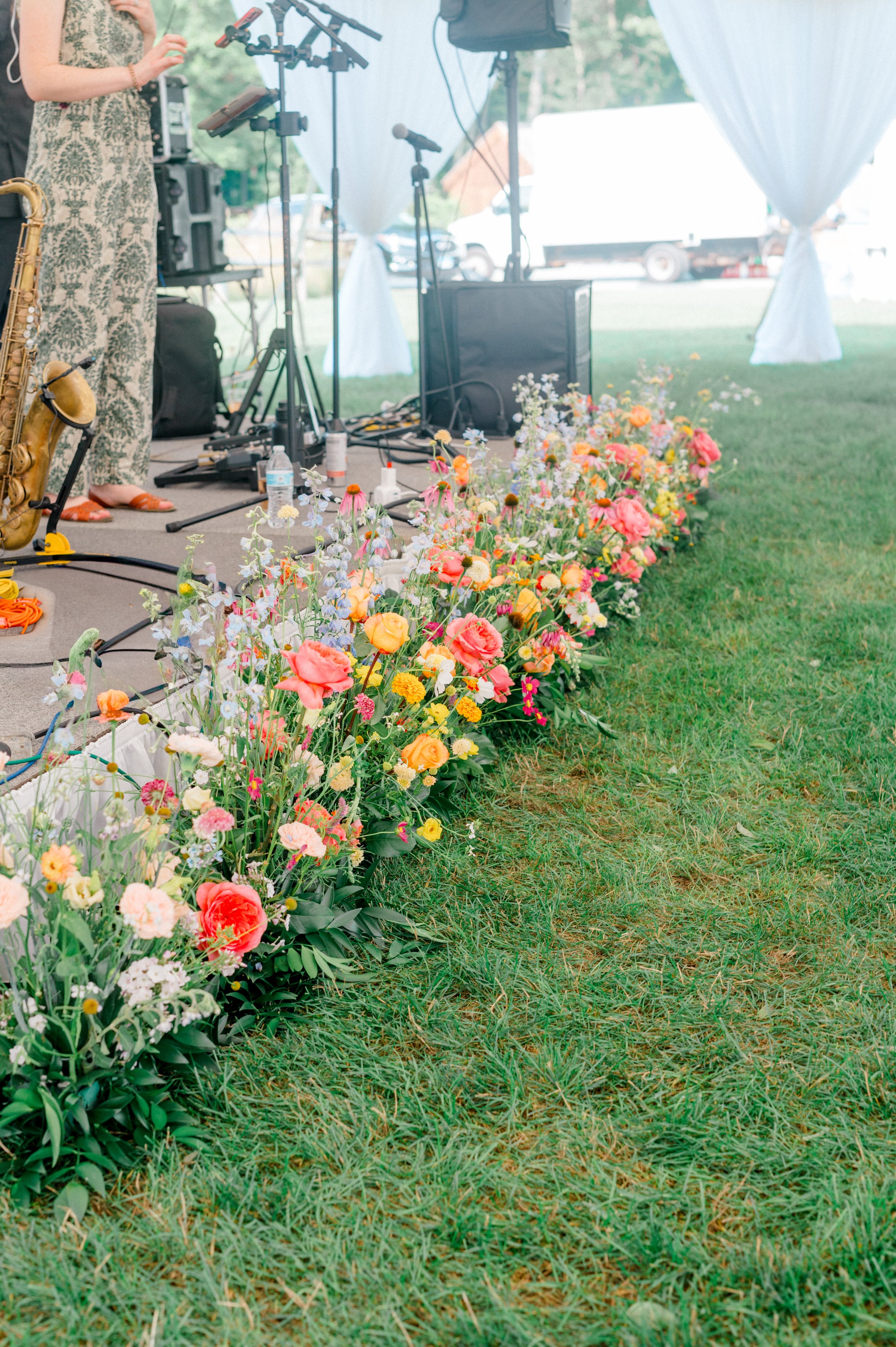 Grounded floral arrangement of zinnias, sweet pea, and garden roses accenting a modern seating chart display.