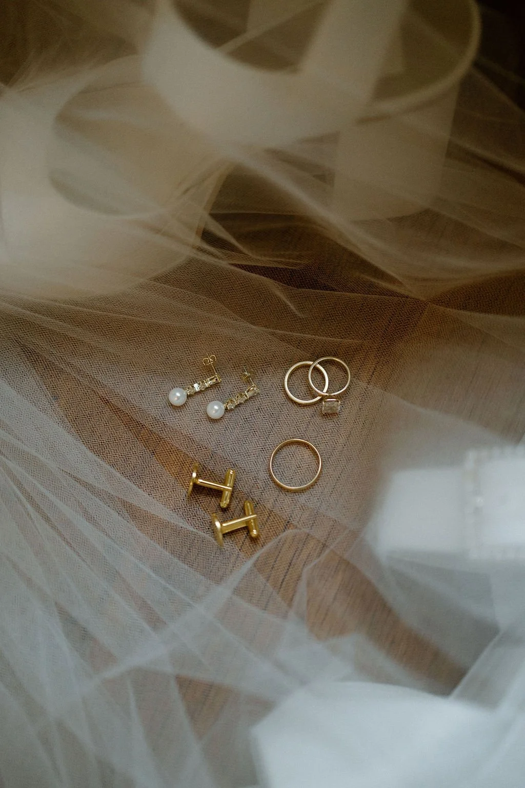 Wedding rings styled on soft ivory fabric with delicate bridal accessories and warm gold details.