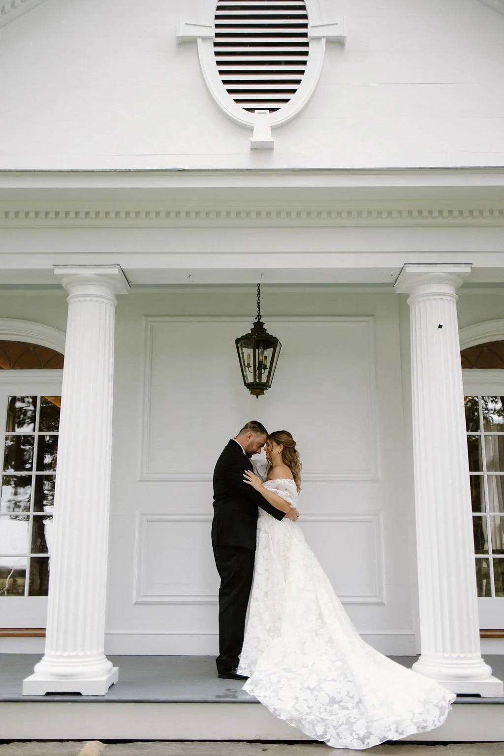 Bride standing in her white wedding gown beneath the classical portico at Smith Farm Gardens in Connecticut.