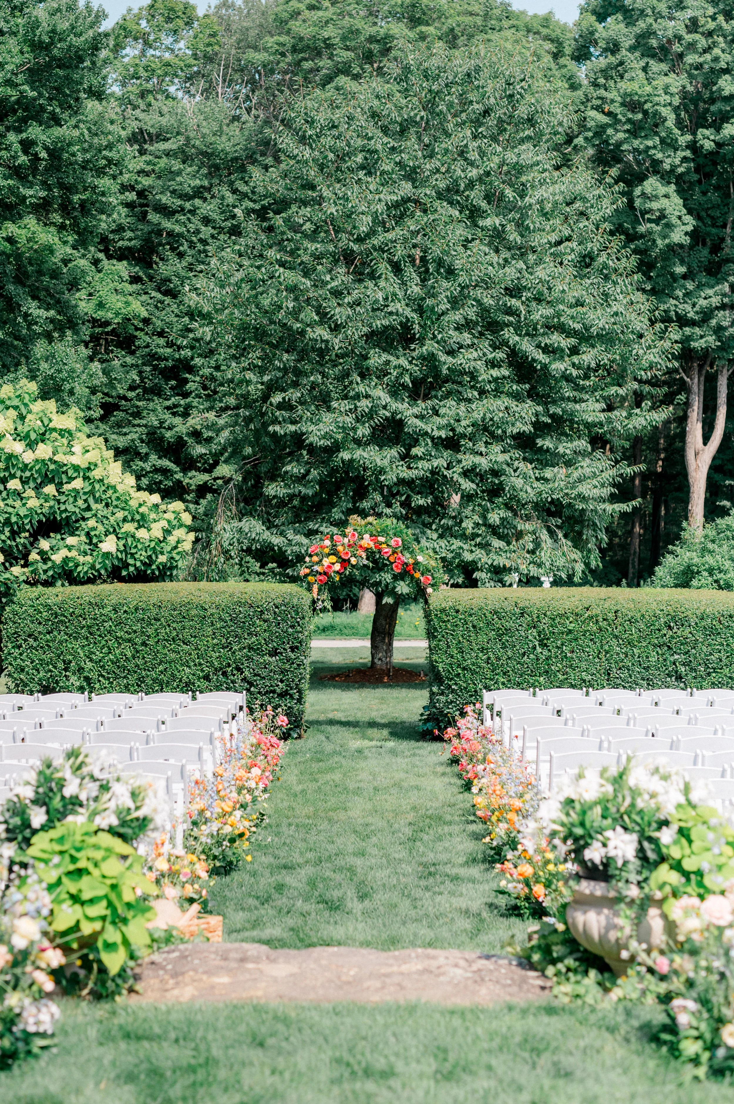 Floral arch hedge accented with magenta blossoms for a romantic summer ceremony.