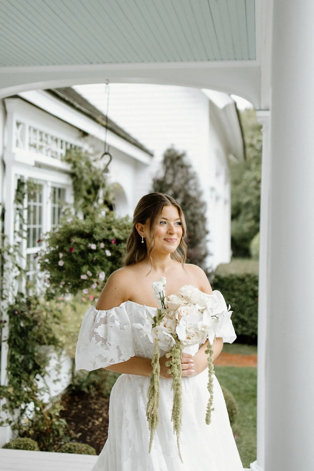 Bride holding a romantic white and neutral garden-style wedding bouquet outside the estate.