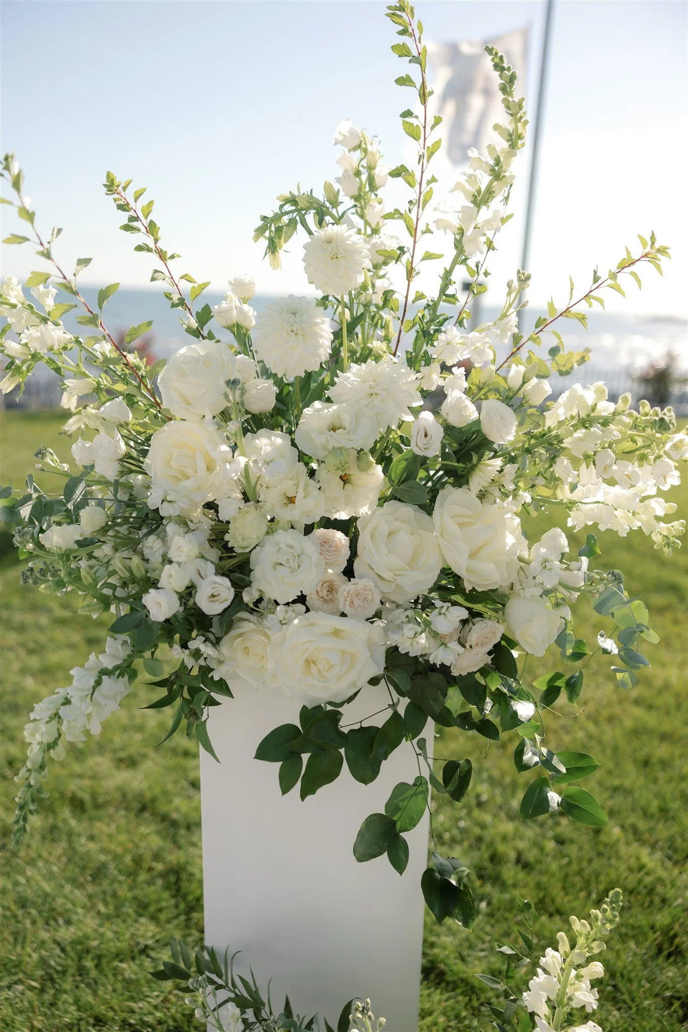 Close-up of textural white roses, lisianthus, campanula, and stock arranged on top of a ceremony column.