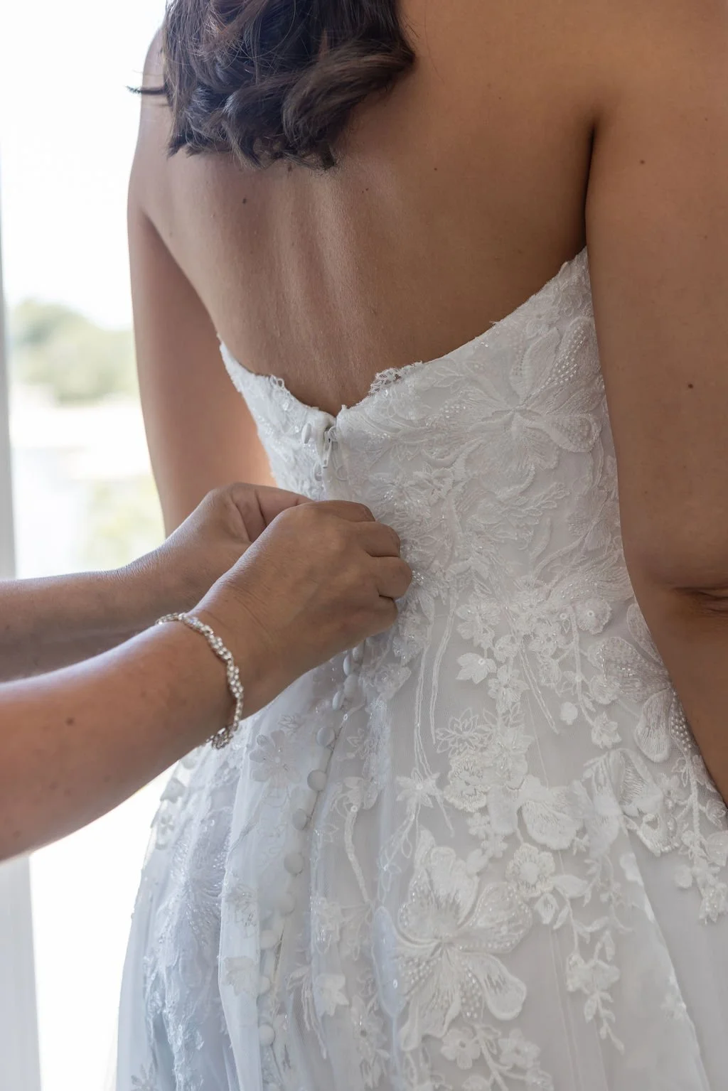 Bride in a lace wedding gown with pearl buttons on the grounds of Water's Edge Resort and Spa Westbrook Connecticut