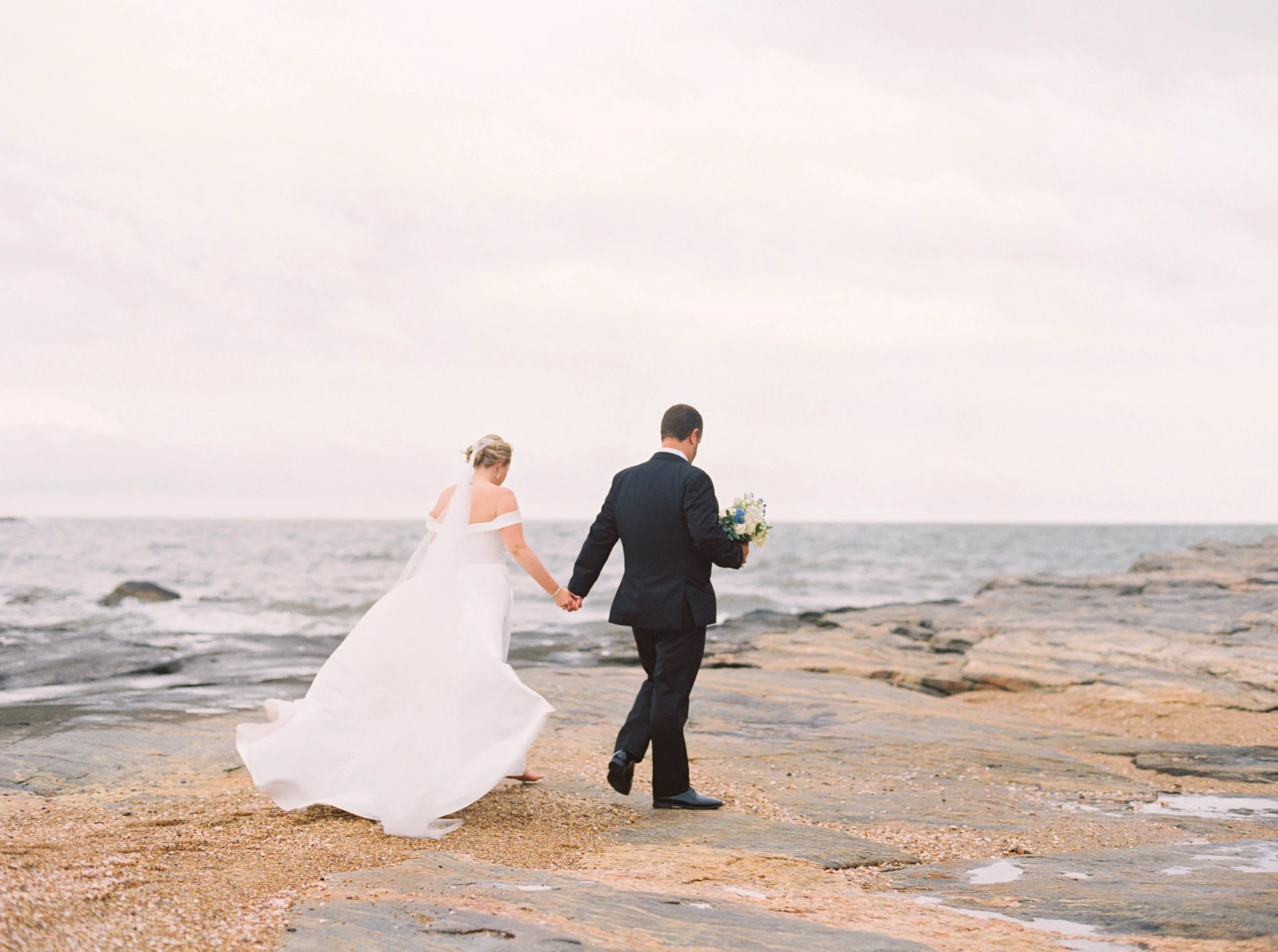 Bride holding white-and-blue garden bouquet at Madison Beach Hotel, designed by First Blush Floral Design Connecticut.