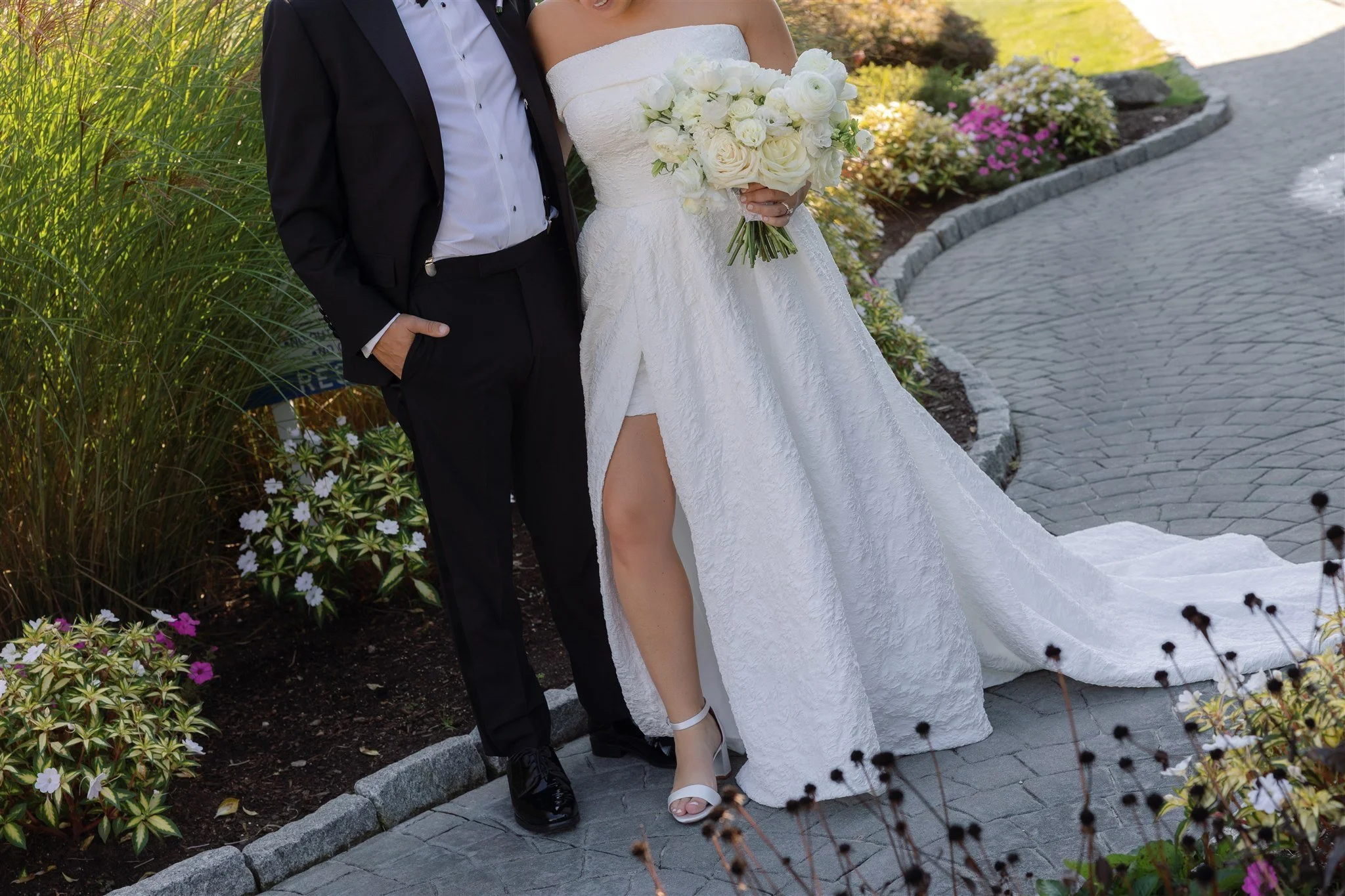 Lush white bridal bouquet with garden roses, ranunculus, spray roses, and lisianthus, tied in ivory ribbon for a timeless coastal wedding look.