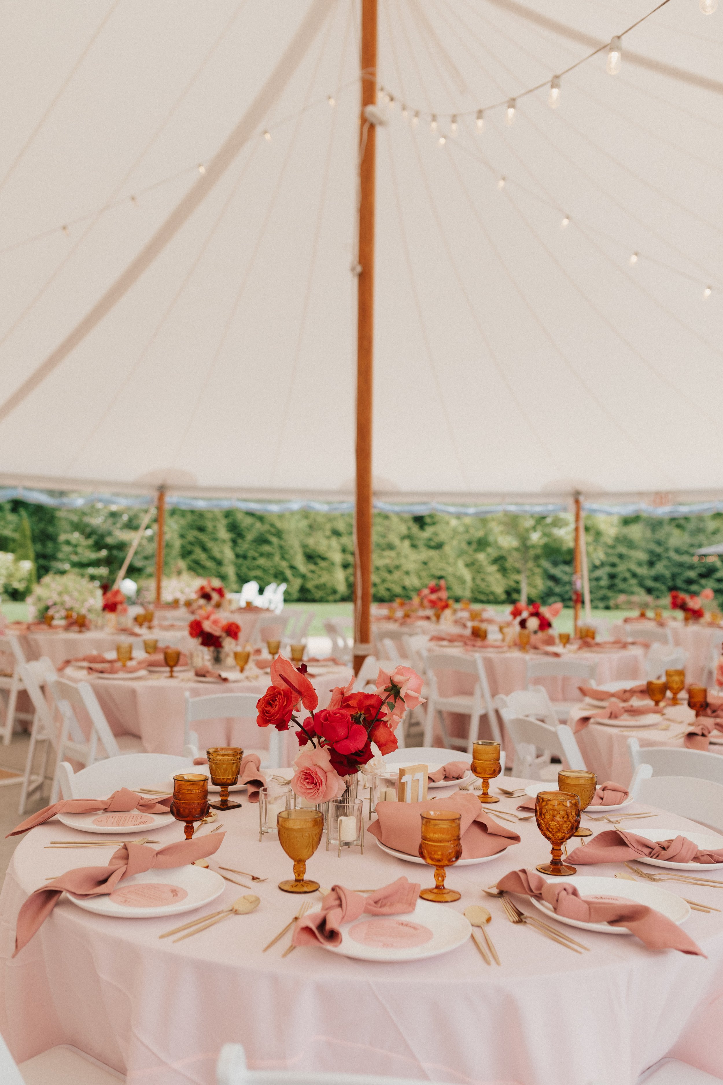 Reception table with colorful roses and anthuriums in modern fluted glass cylinders.