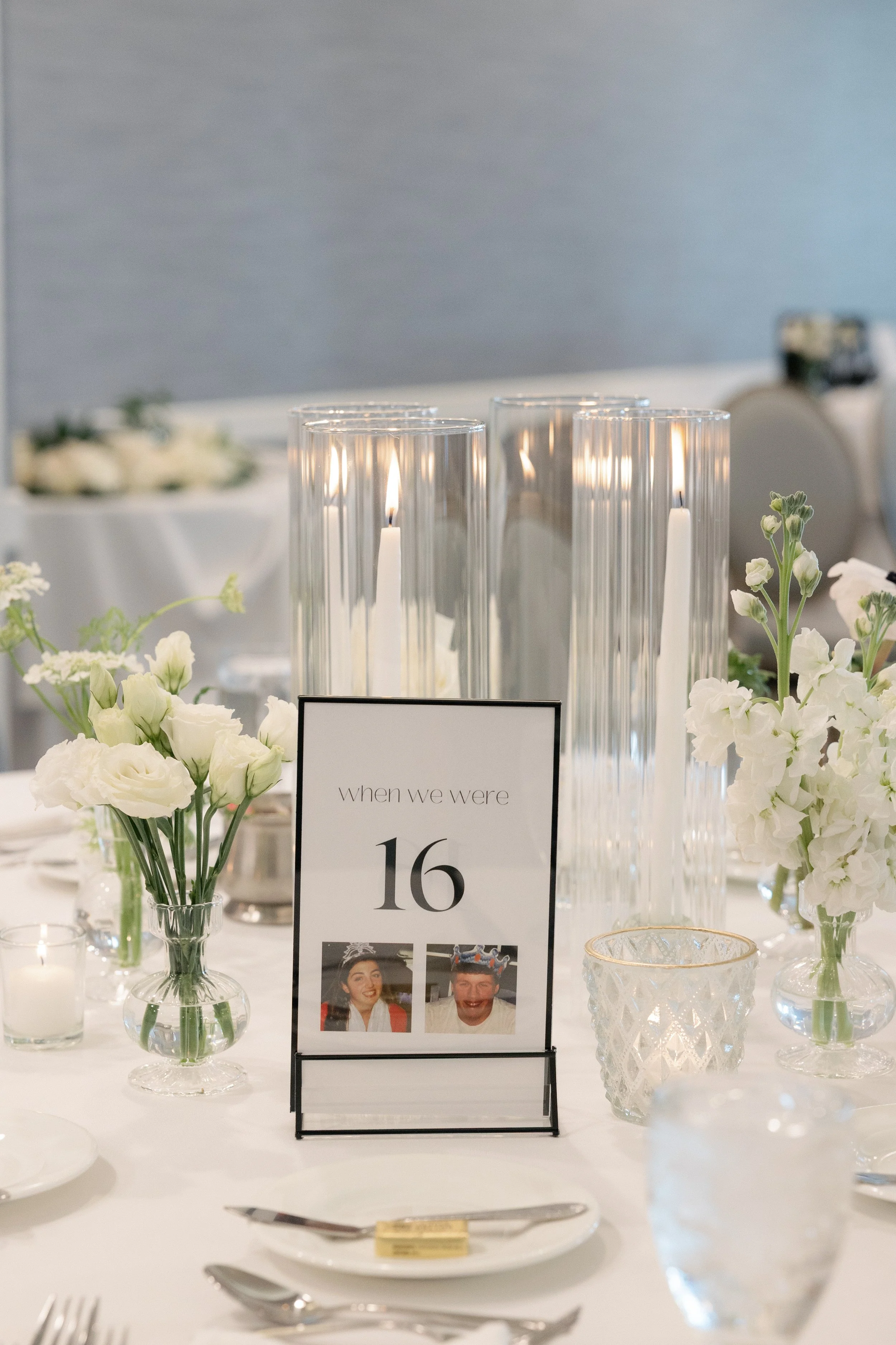 Tall ivory taper candles interspersed with all white blossoms in elegant tall budvases.