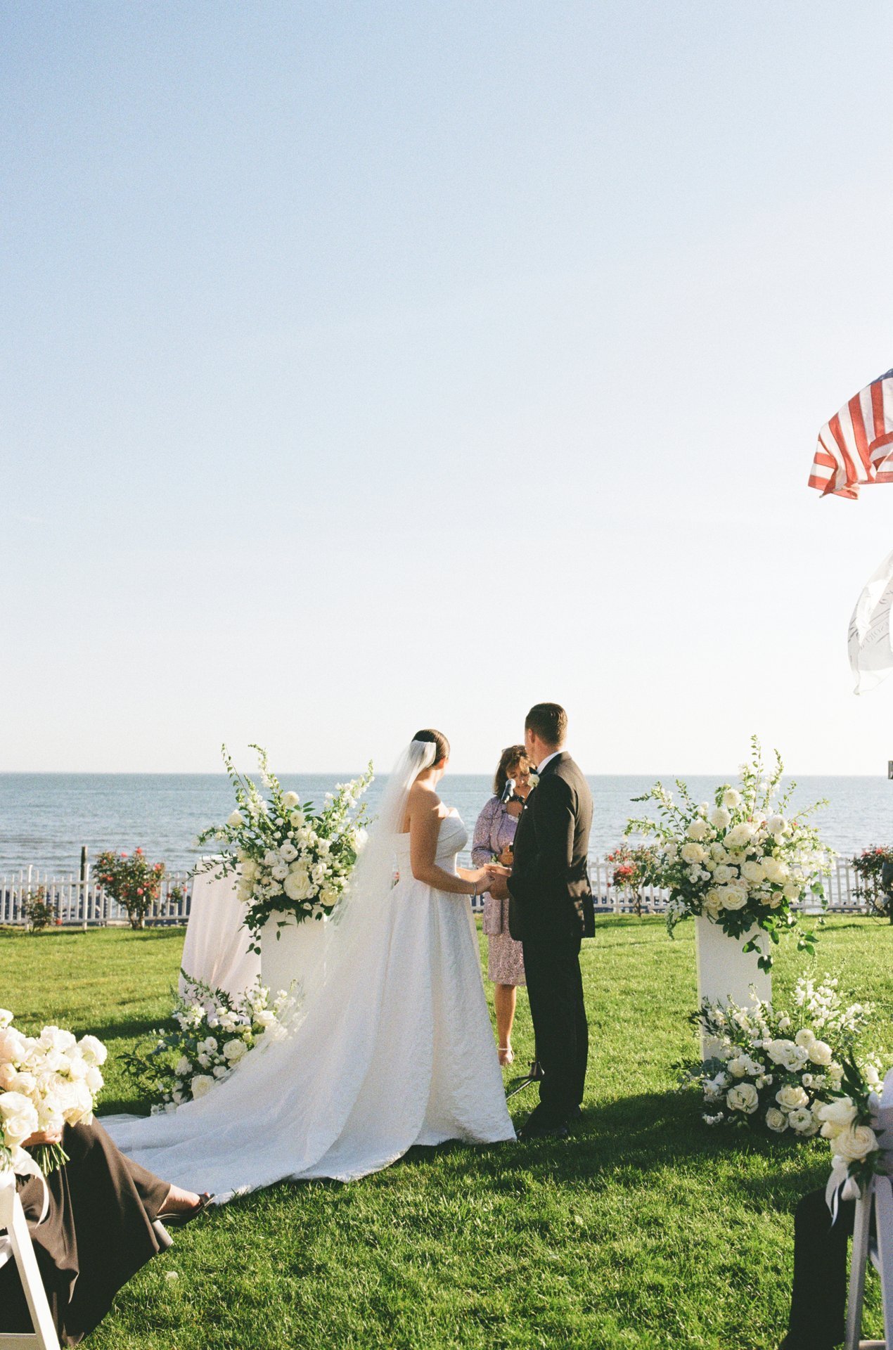 Coastal ceremony with two white floral columns topped with airy garden-style arrangements overlooking the ocean