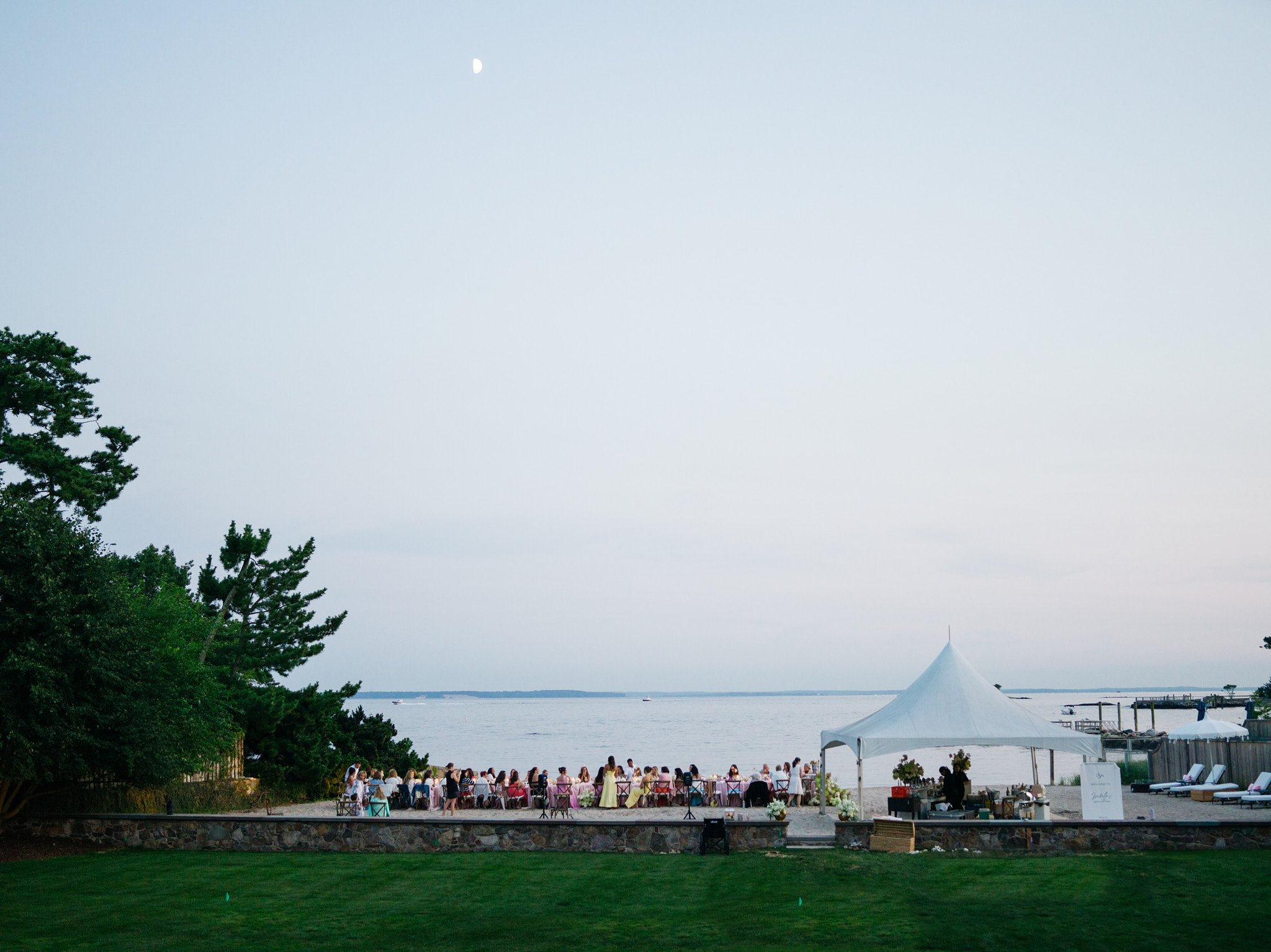 Guests seated at beachside dinner tables with waves in the background, private Connecticut coastal residence