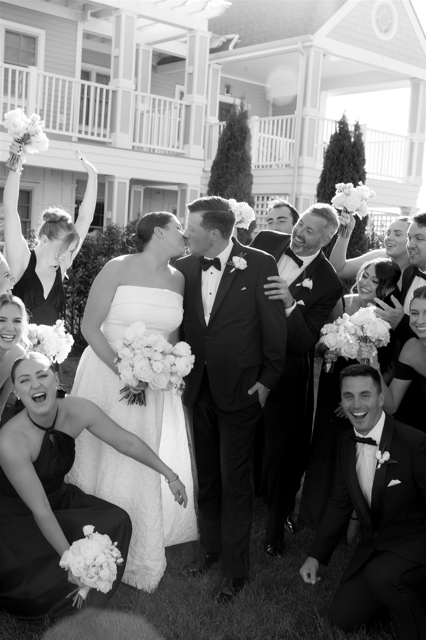Wedding party in coordinated white and neutral tones against a waterfront backdrop.