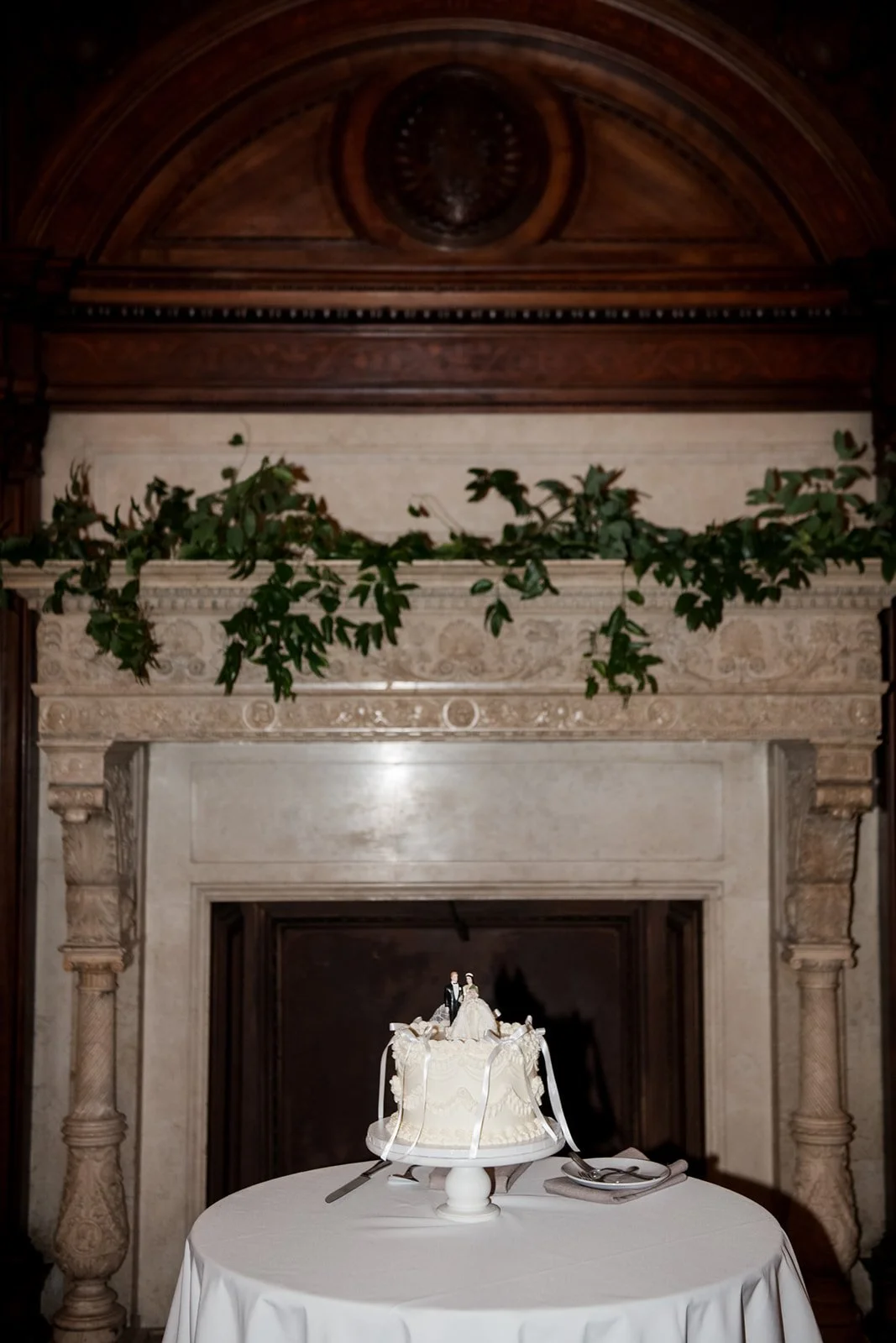 Classic white Lambeth-style wedding cake featuring ornate piping and a vintage figurine topper.