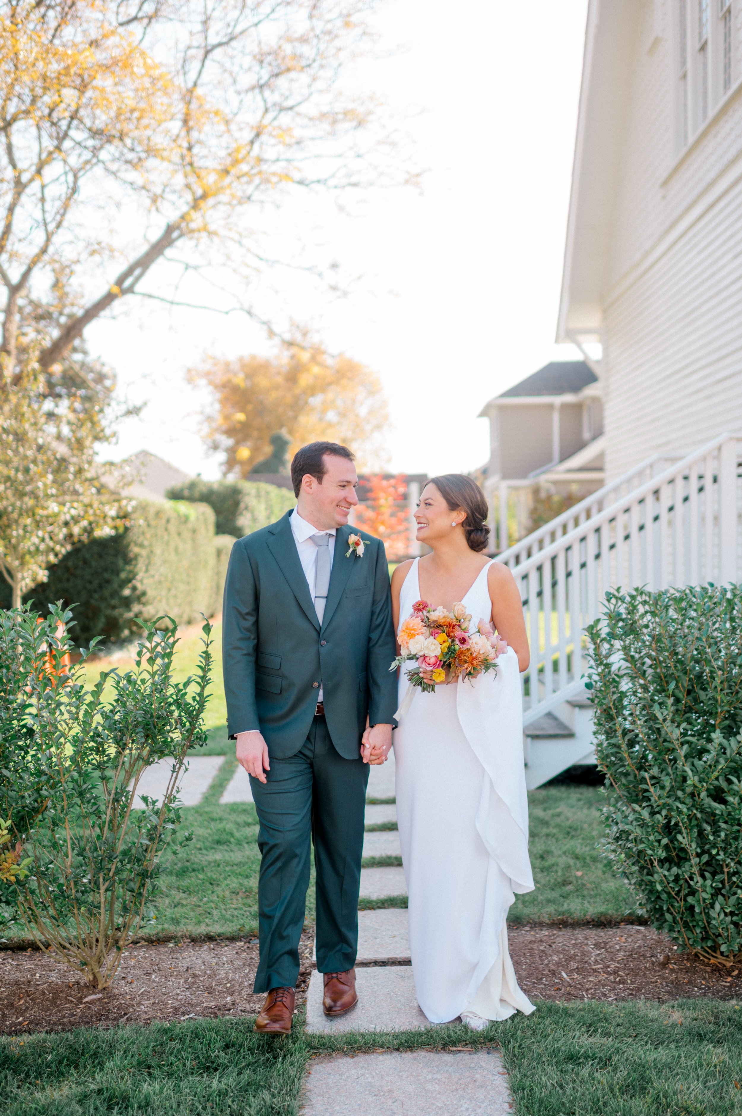 Bride and groom in a seaside embrace with her vibrant fall bouquet front and center