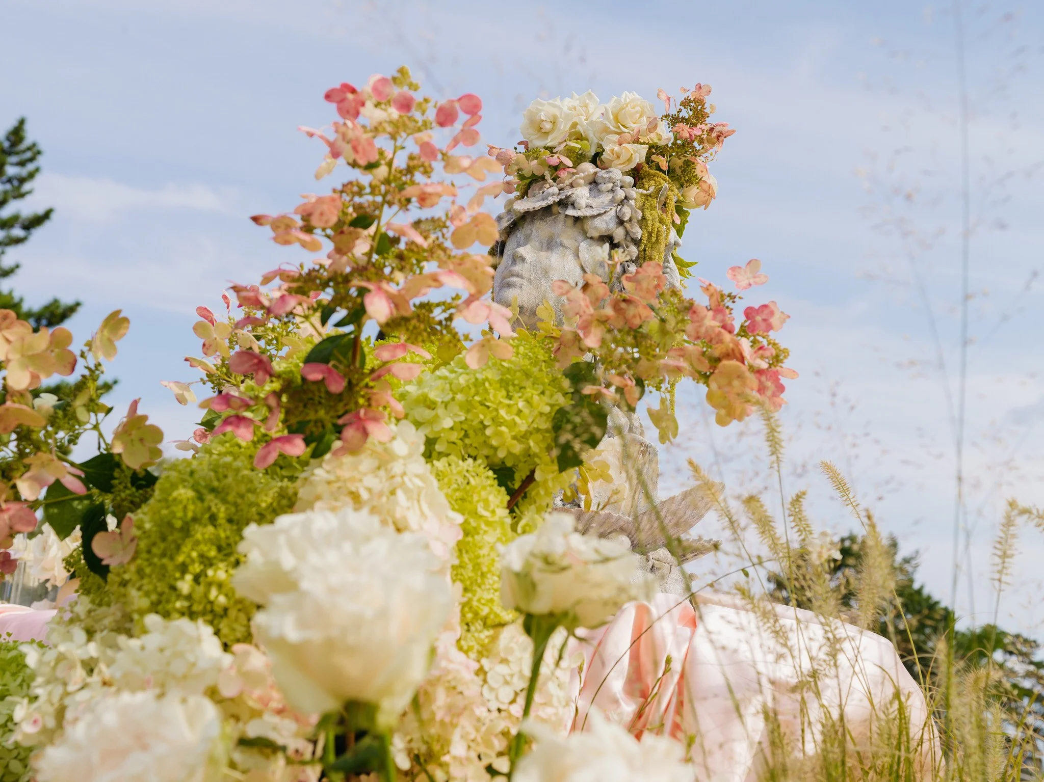 Sculptural bust anchoring the beachside floral installation at golden hour, coastal Connecticut bridal shower