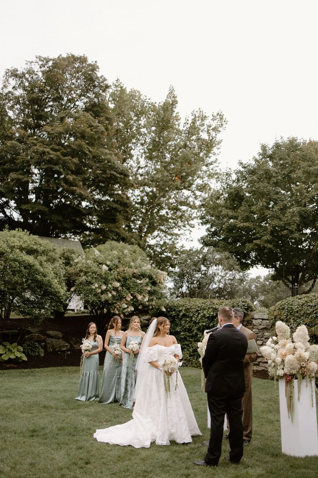 Bridal party standing together during an outdoor garden wedding ceremony.