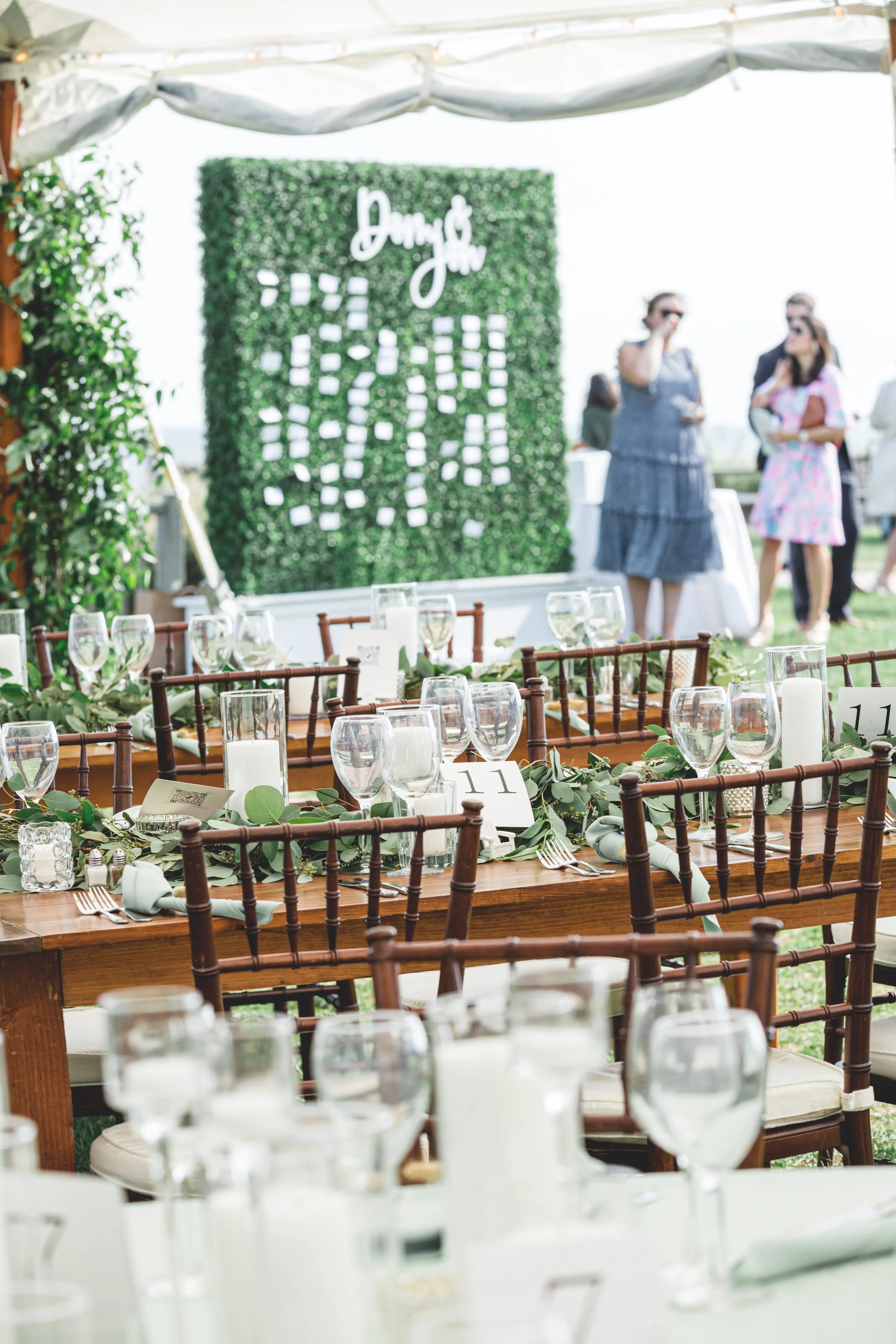 A lush eucalyptus garland runs the length of a wooden table, tucked between glowing pillar candles in glass hurricanes and wine glasses.