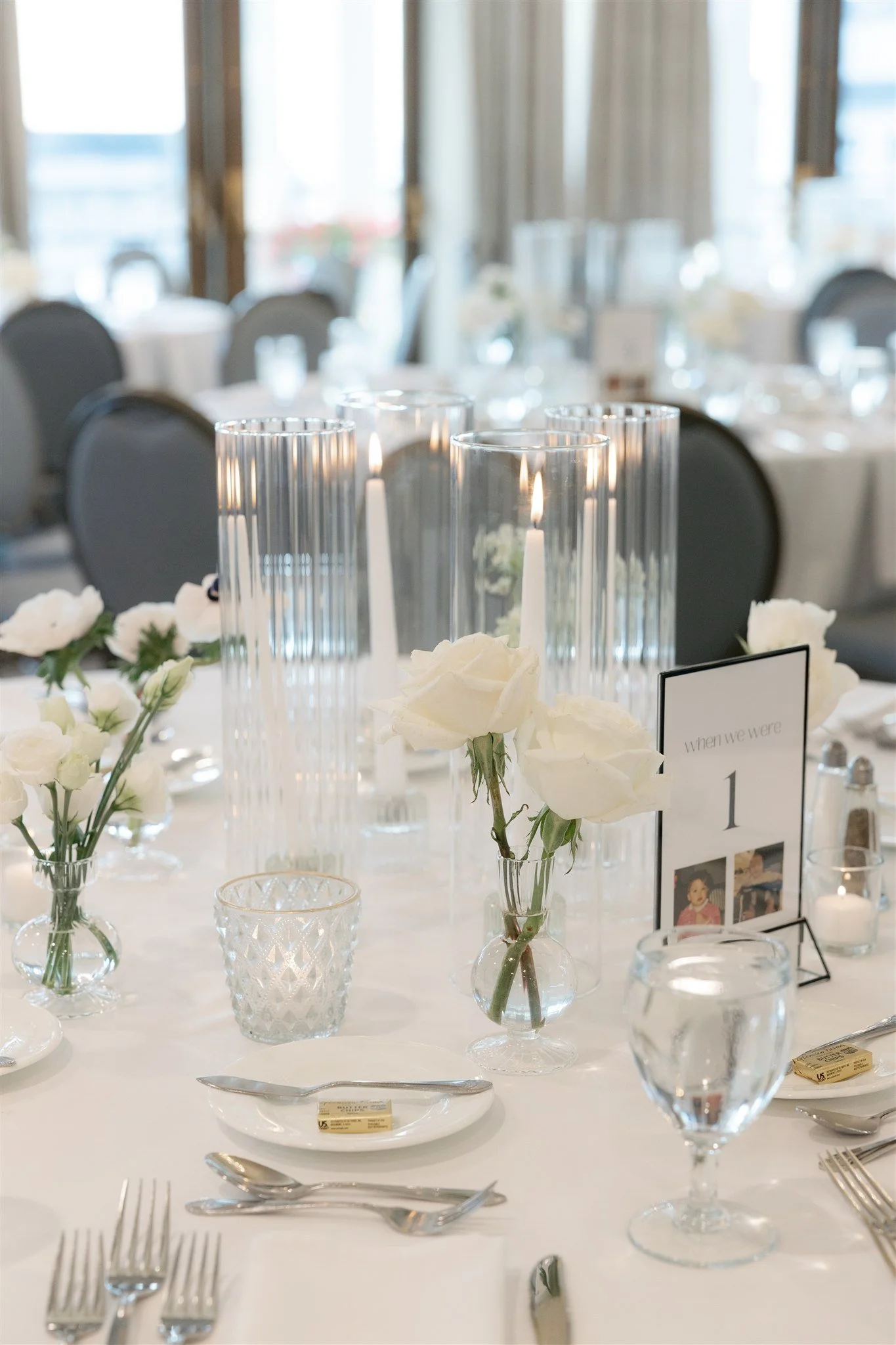Minimalist centerpiece with white roses and greenery paired with candle clusters for an understated luxury look.