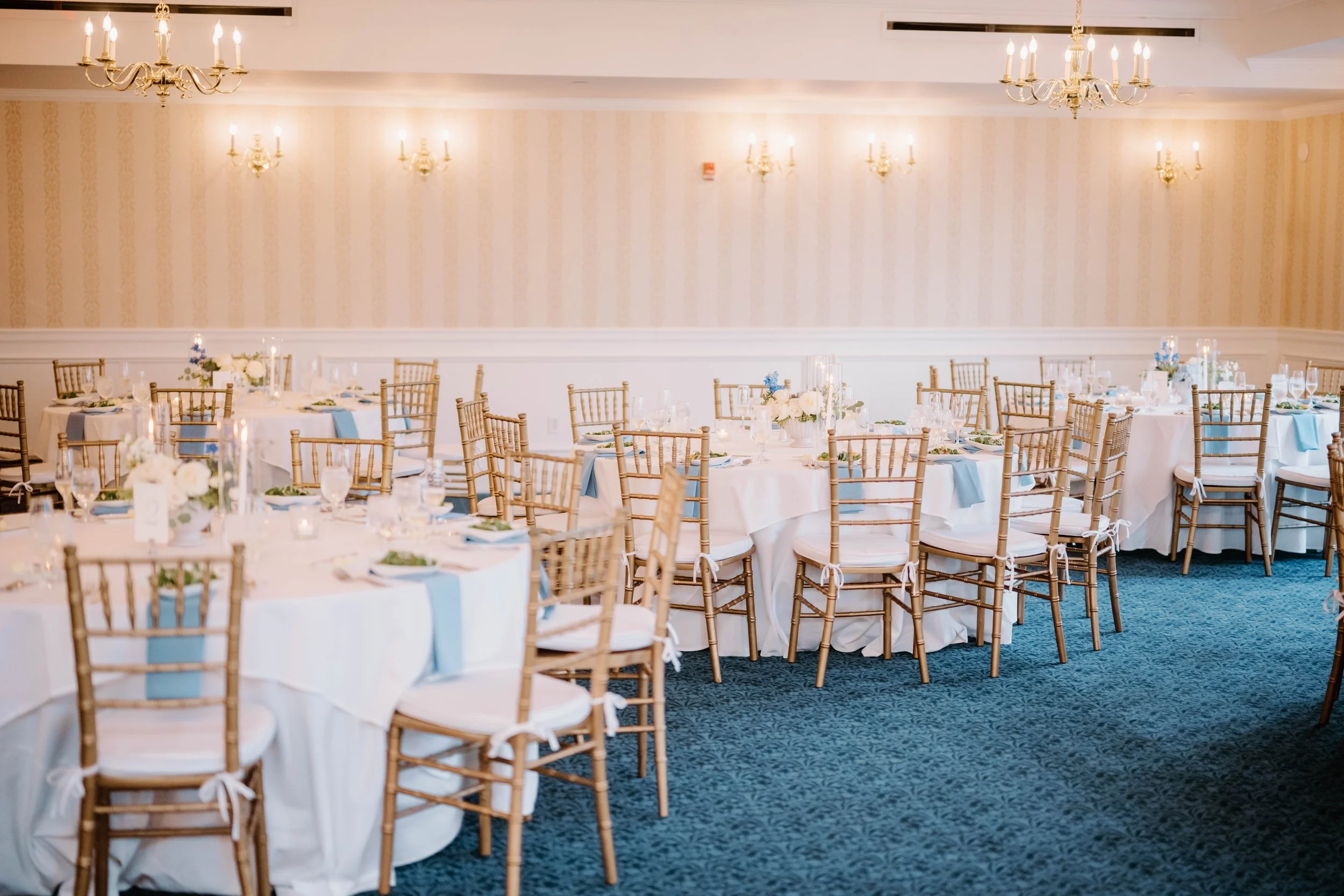 Reception tables styled with white linens, blue napkins, and romantic taper candles at Madison Beach Hotel.