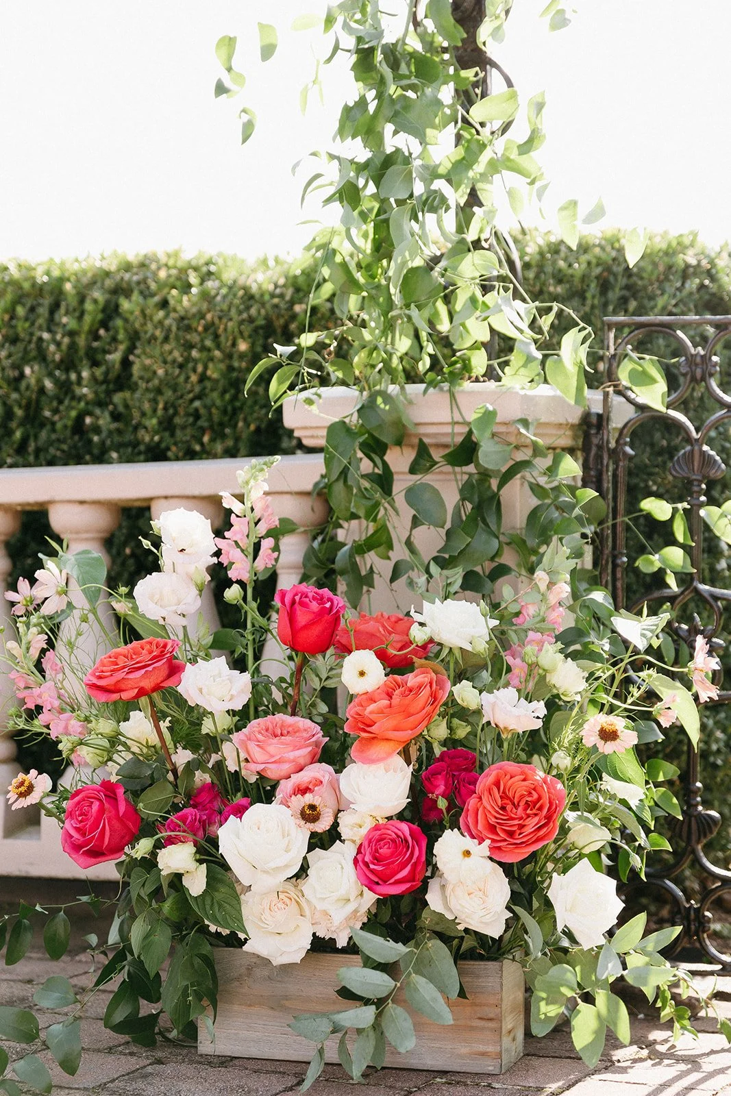 Lush ceremony floral arrangement featuring coral, pink and white blooms with trailing greenery at a Wickham Park garden wedding.