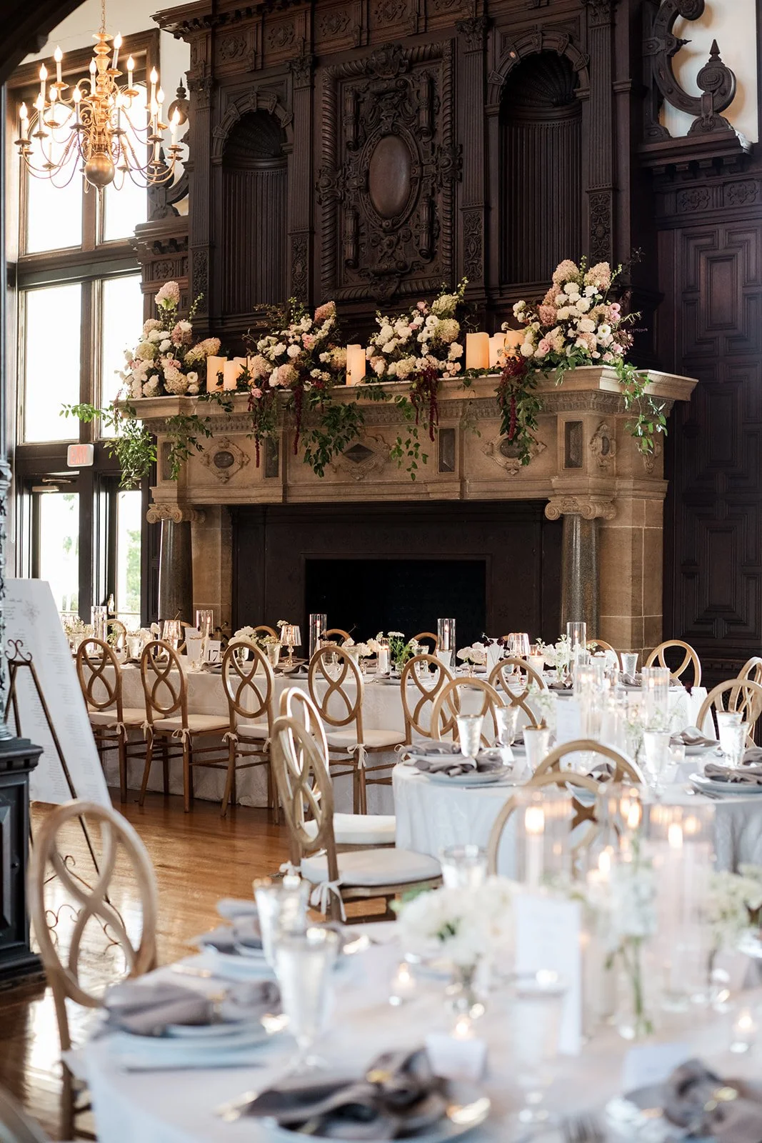 Floral installation on the historic Branford House mantle with trailing greenery and oversized candles.