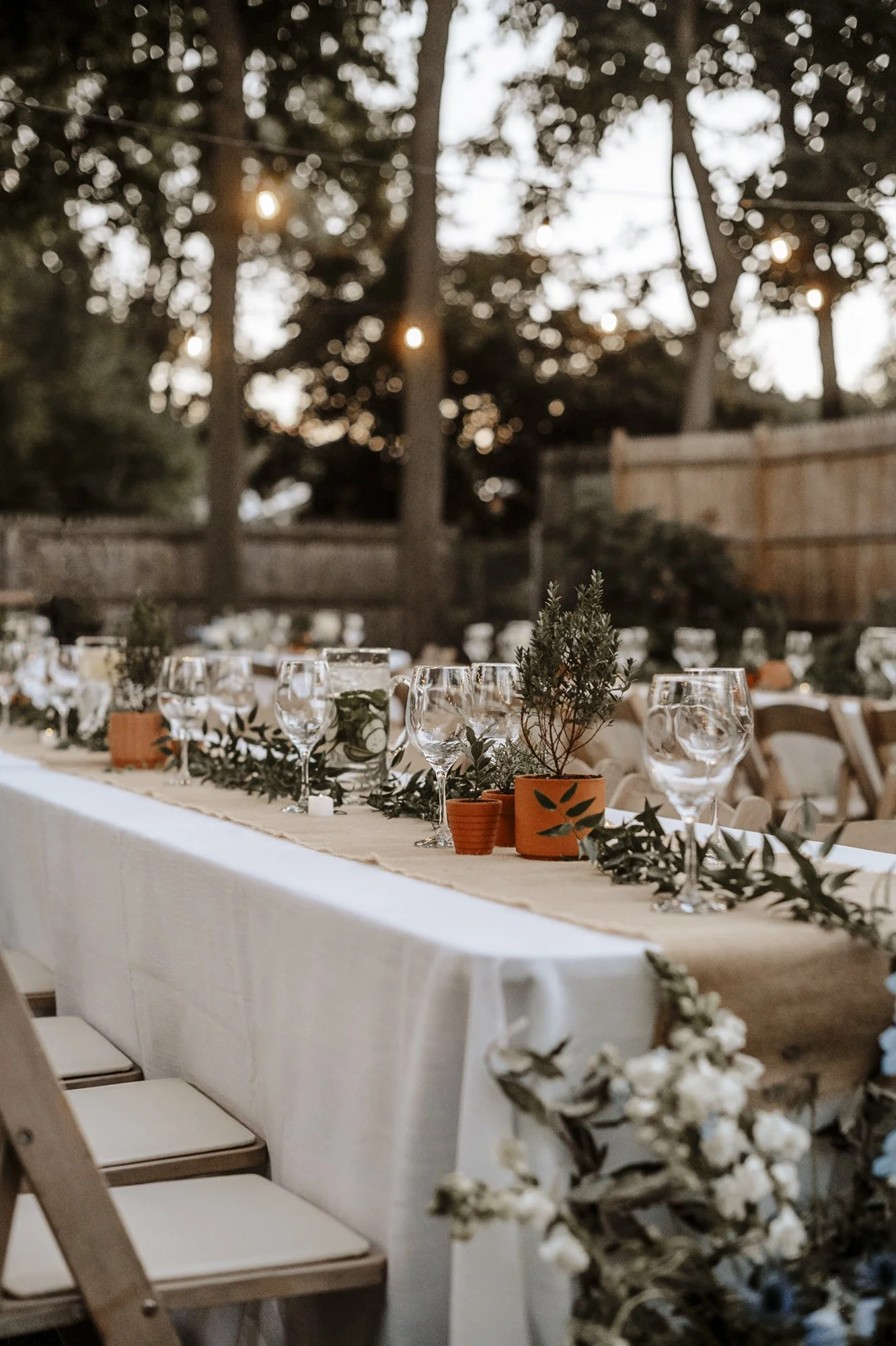 Long backyard wedding reception table with sprigs of Italian ruscus laid stem to stem down the center, at a private home in Hamden, CT