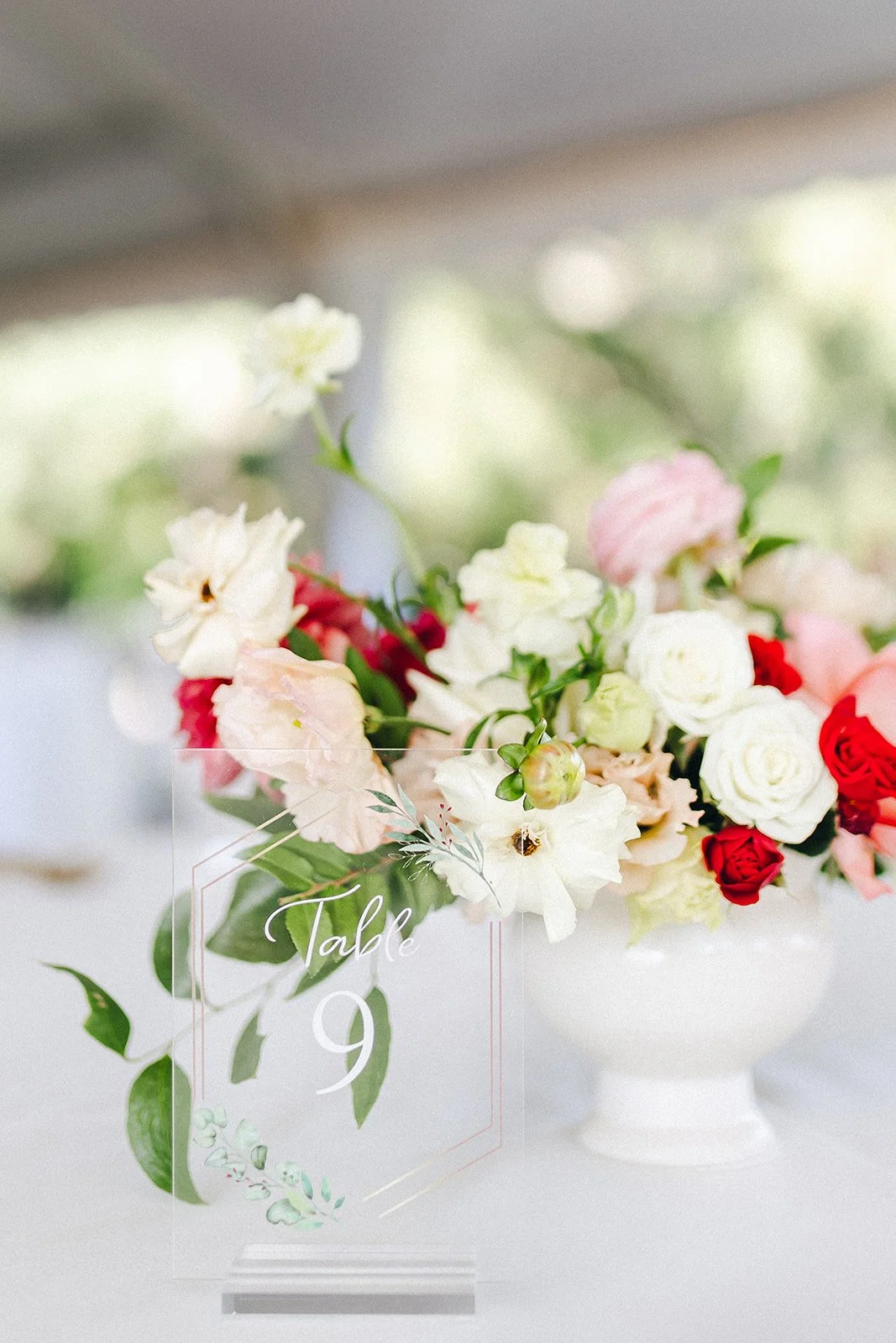 Elegant white urn centerpiece filled with pink, coral, red and ivory flowers with delicate greenery for a Wickham Park wedding reception.