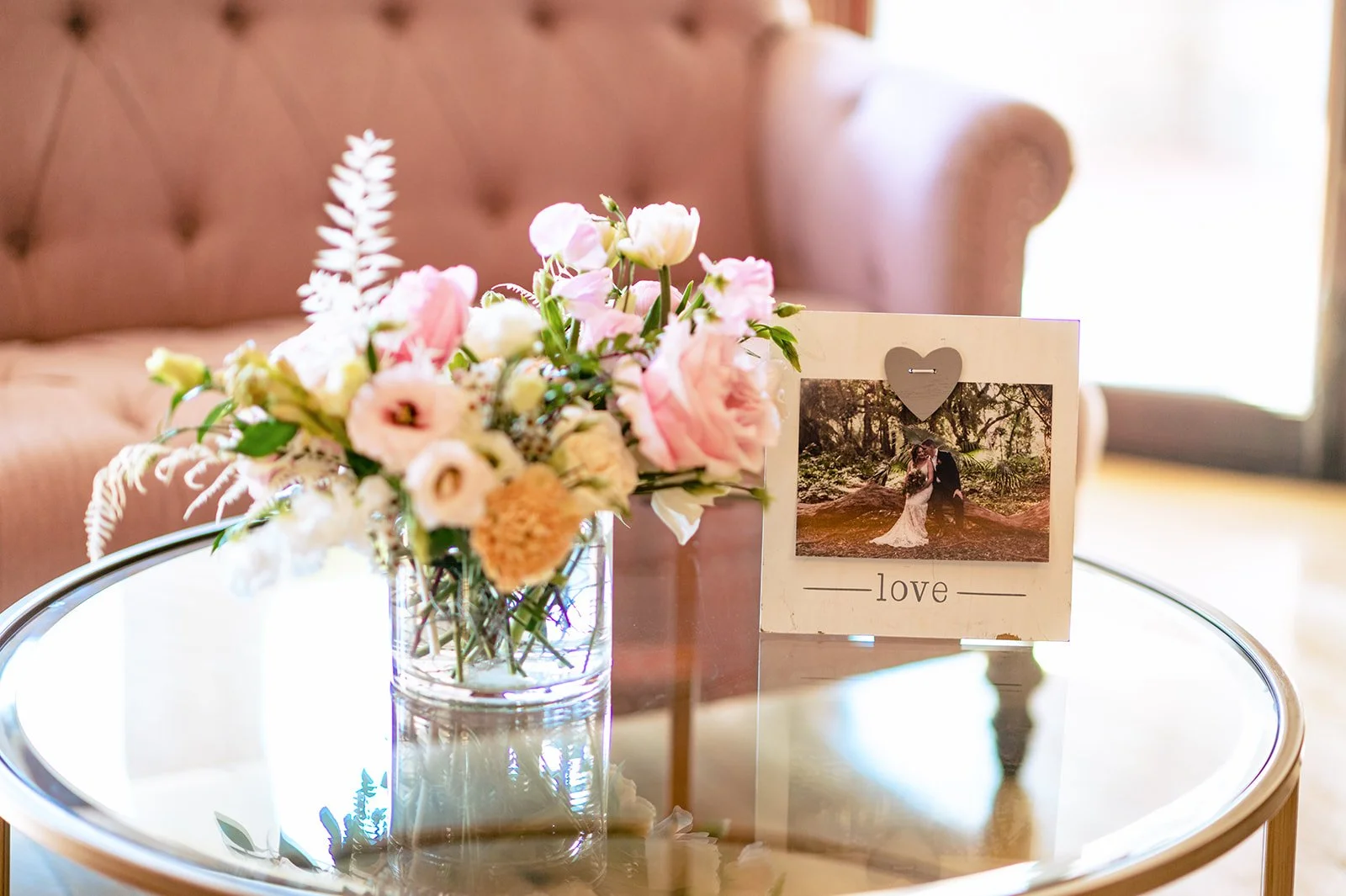 The couple’s personal photos tucked among greenery and candlelight on a wedding reception mantel at Branford House