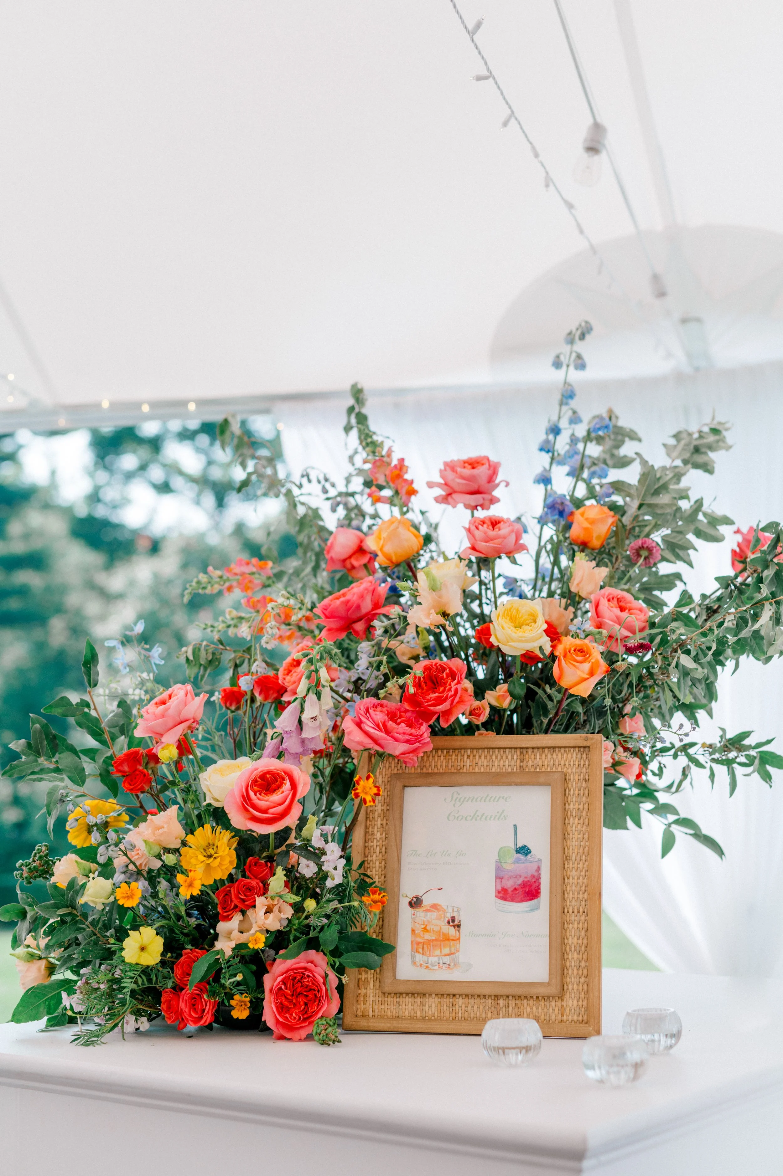 Repurposed ceremony florals framing the wedding bar for a cohesive garden design.