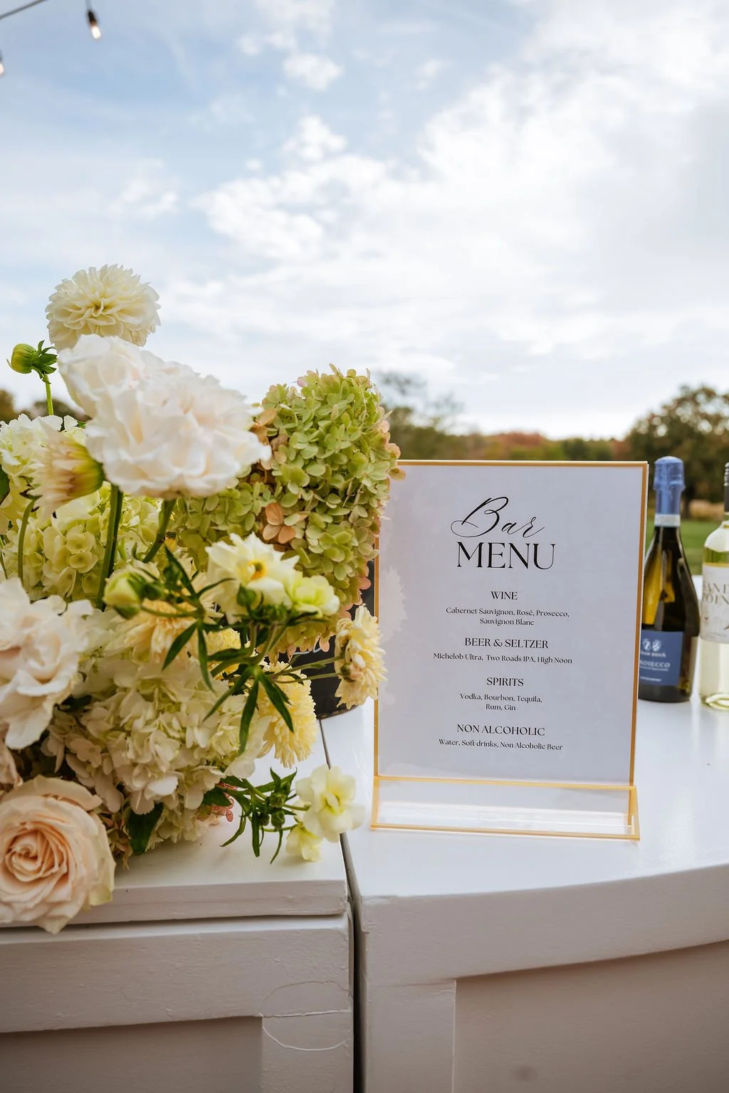 Bar menu and floral installation with limelight hydrangea at outdoor wedding cocktail hour