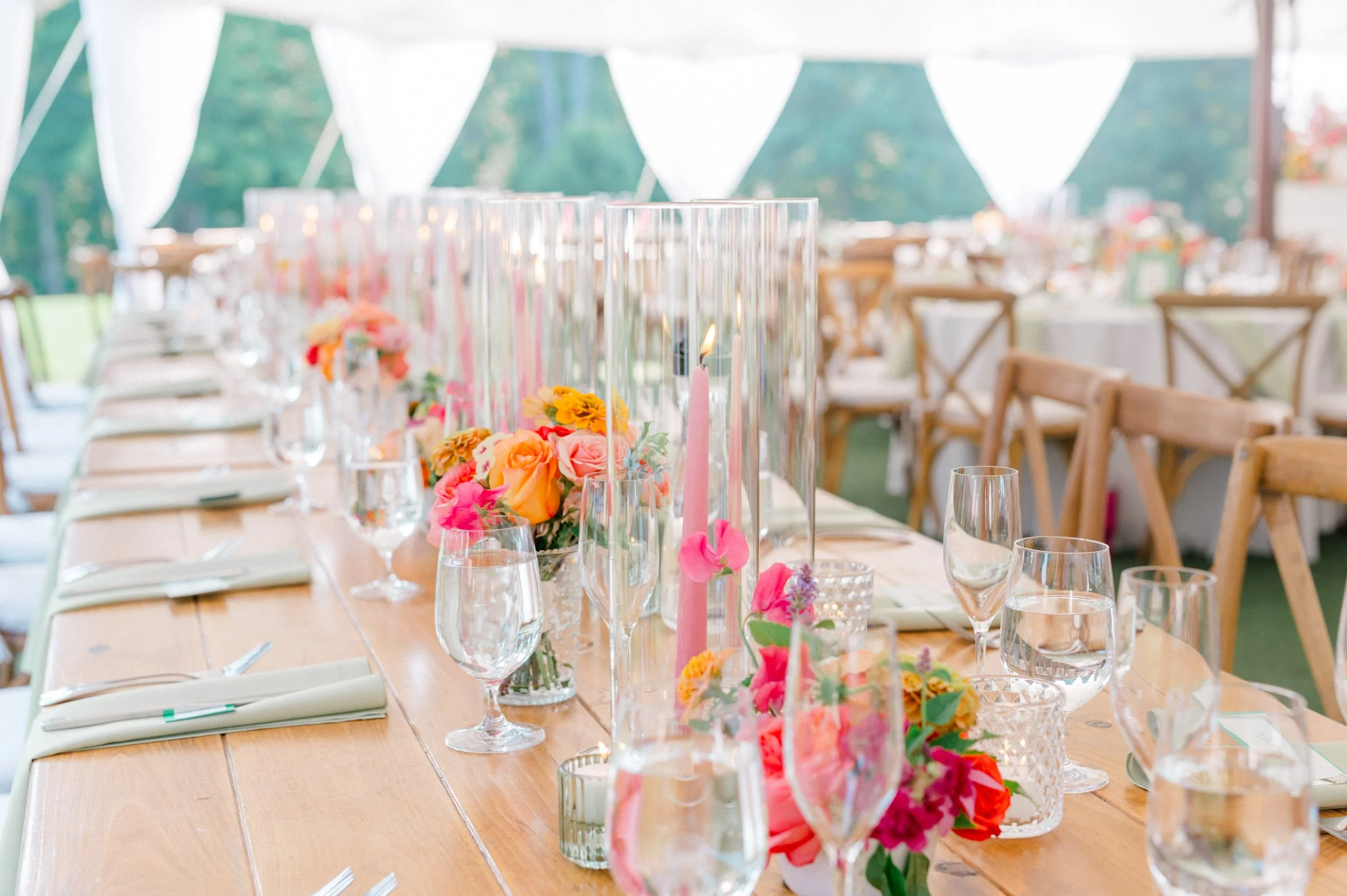 Head table styled with soft pink taper candles, bud vases, and lush summer blooms