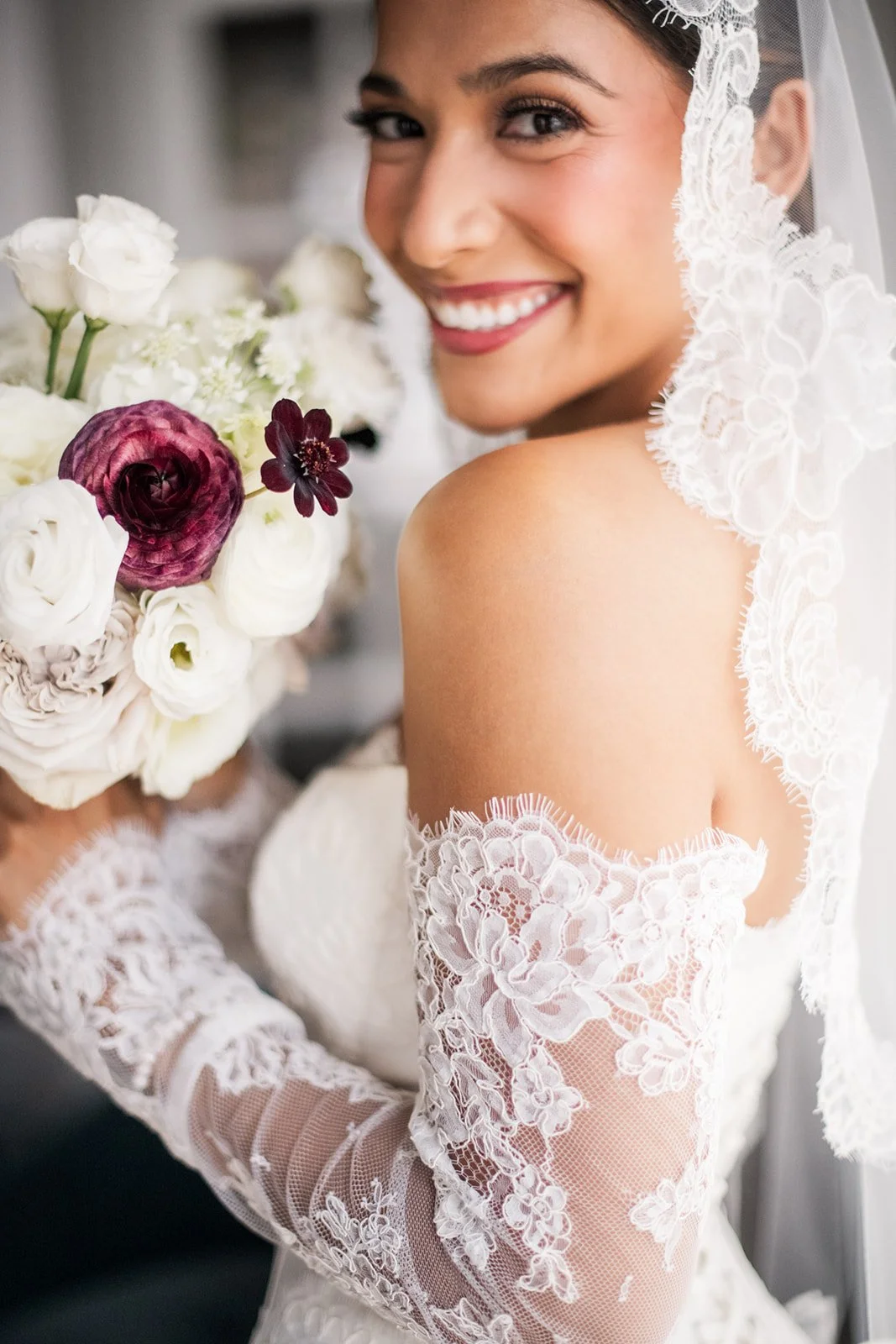 Editorial bridal bouquet with layered white blooms and dramatic plum ranunculus.