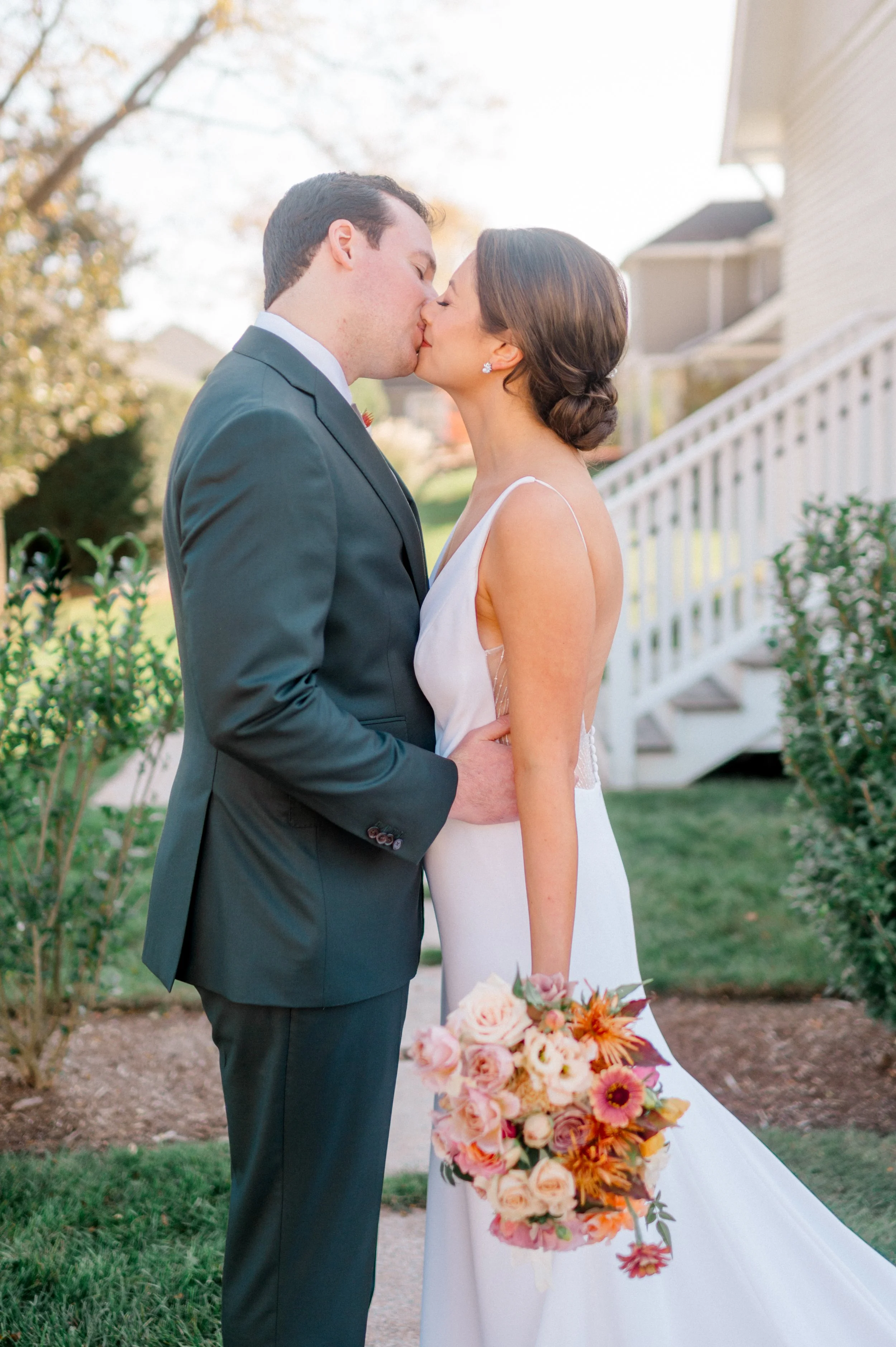 Soft portrait of bride and groom with autumn-inspired bouquet glowing in coastal golden hour.”