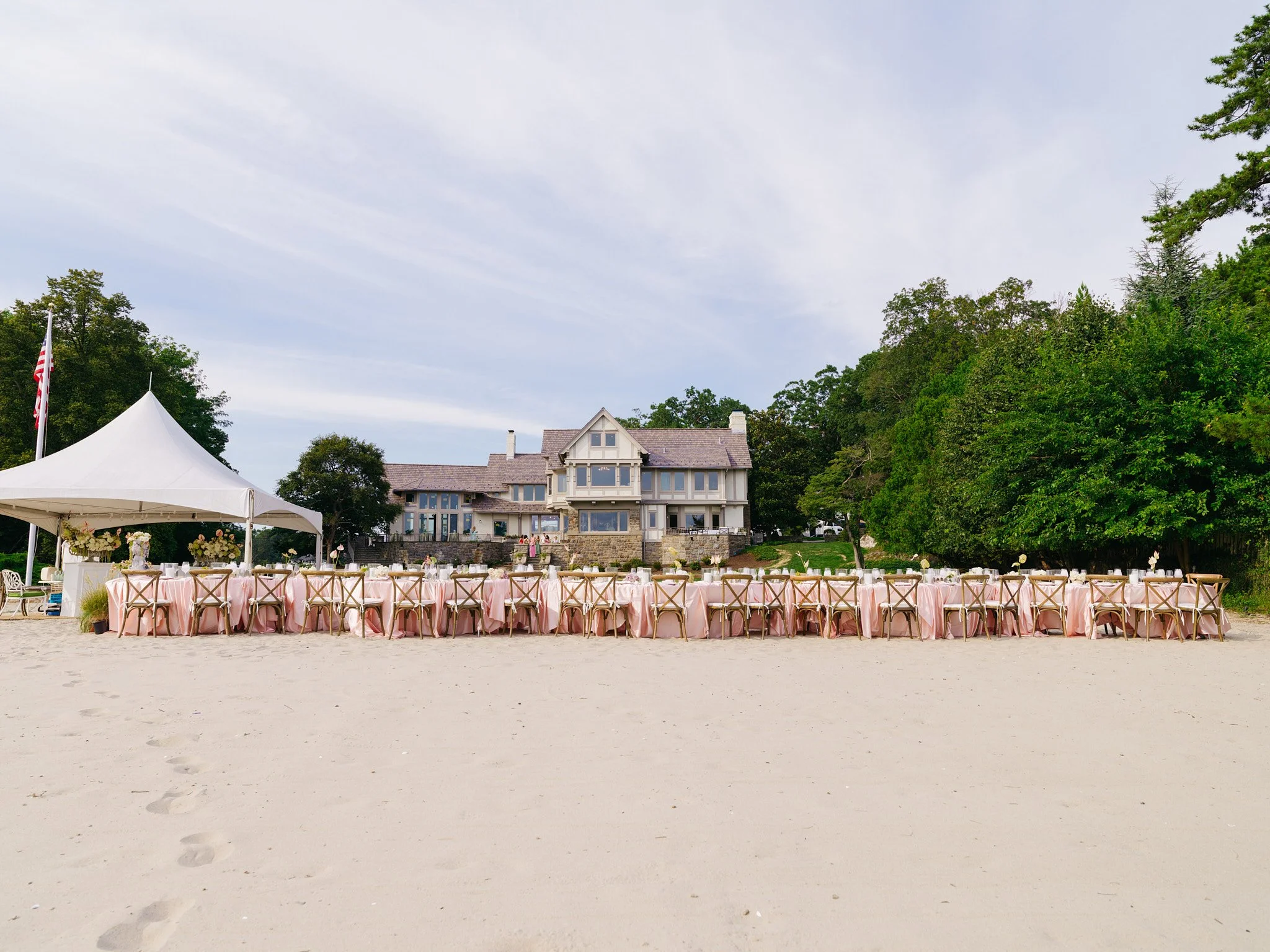 Landscape view of full tablescape with natural wood chairs and minimalist dinnerware from Abbey Tent & Party Rentals, beachside Fairfield County
