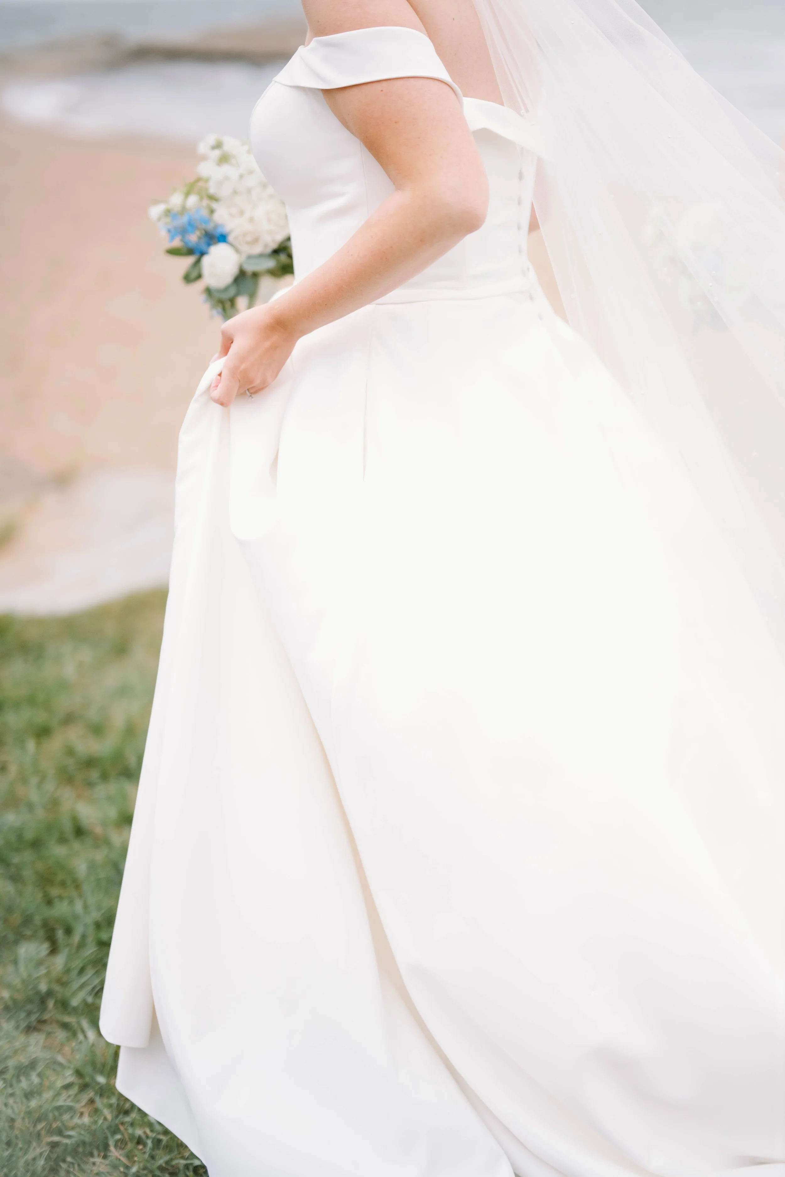 Textural close-up of white dahlias, blue thistle, and tweedia bouquet with natural foliage.