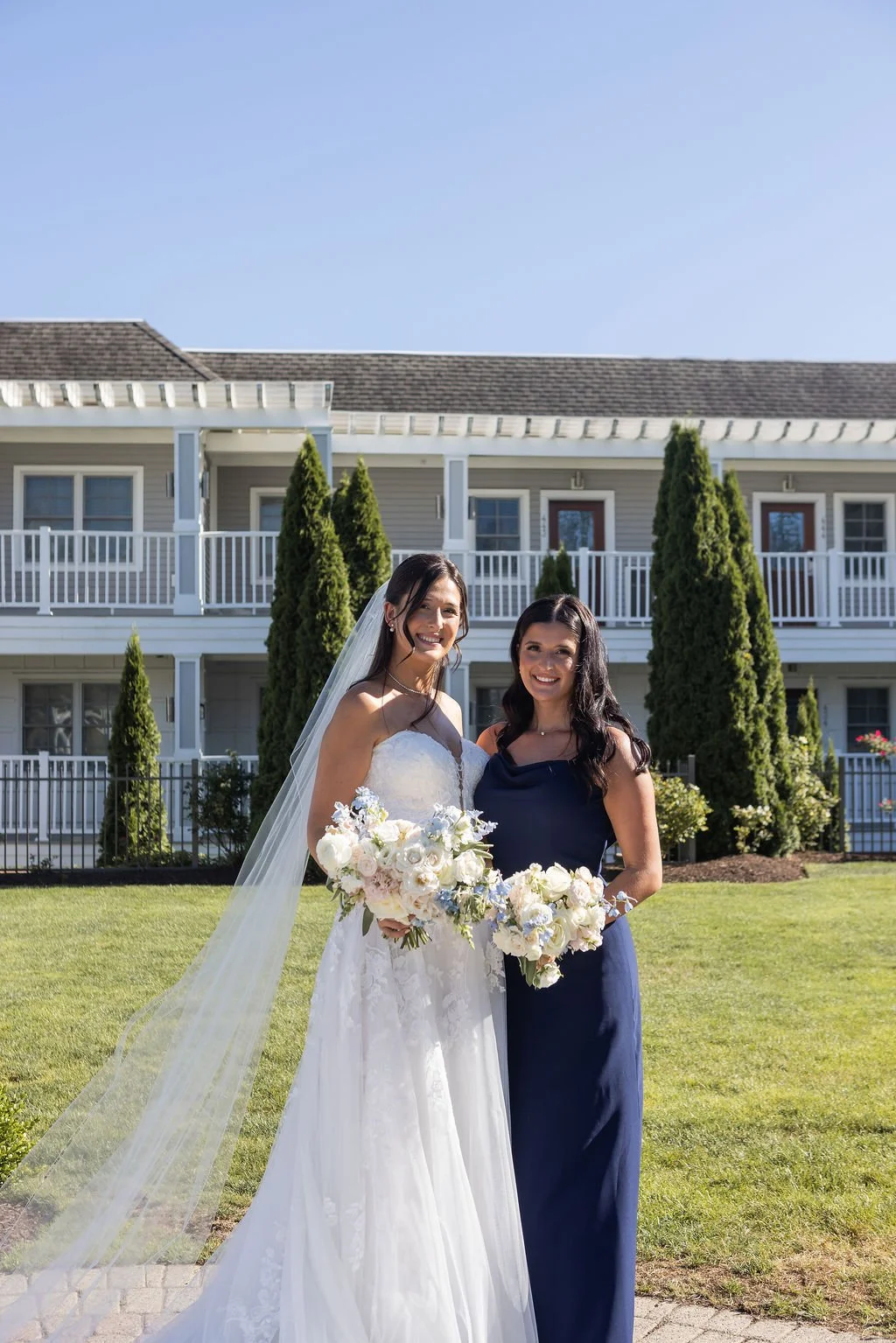 Bride and maid of honor holding garden-style bouquets in white ivory and blue on the lawn at Water's Edge Resort Connecticut, First Blush Floral Design