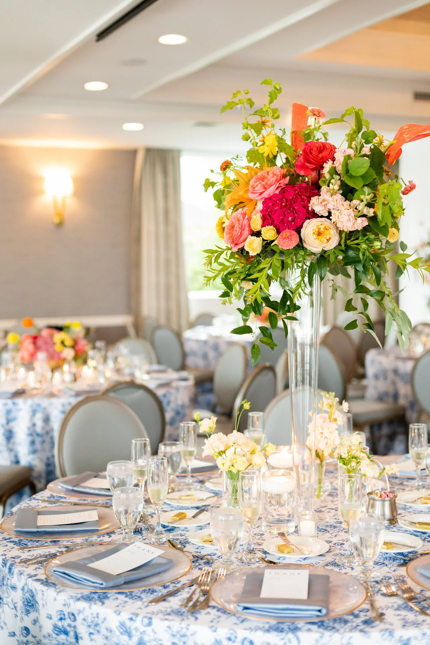 Alternating centerpieces with bold vibrant colors, elevated and gold compotes with lush sunset shades.