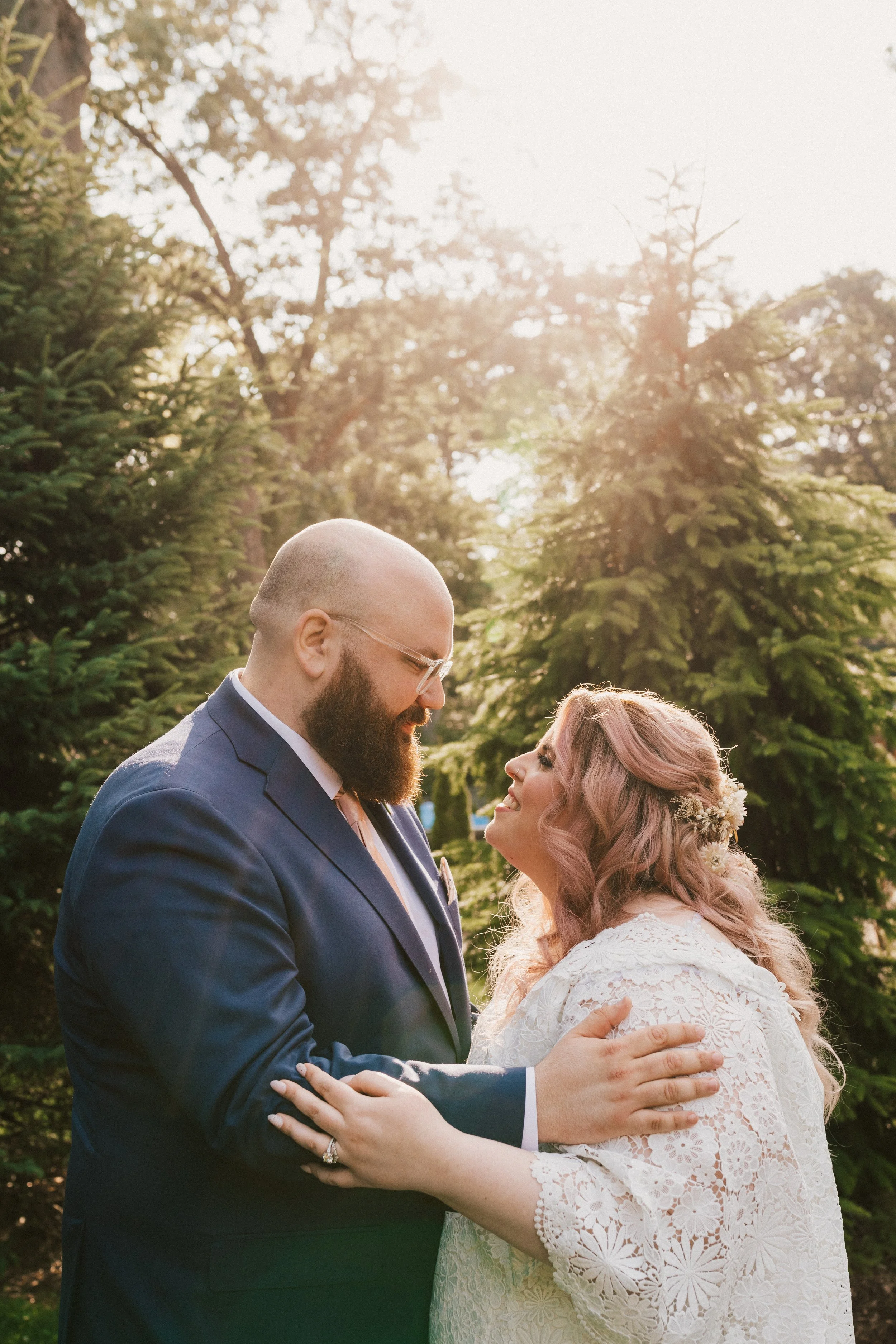 Bride and groom laughing together in a lush, natural setting at The Hops Company’s outdoor garden venue.