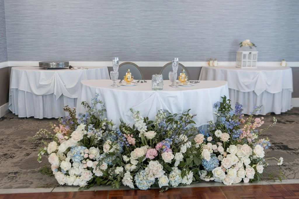Tall urn arrangement with white and blue hydrangea, white roses, and light blue delphinium at the escort card table for a Connecticut wedding at Water's Edge Resort, First Blush Floral Design