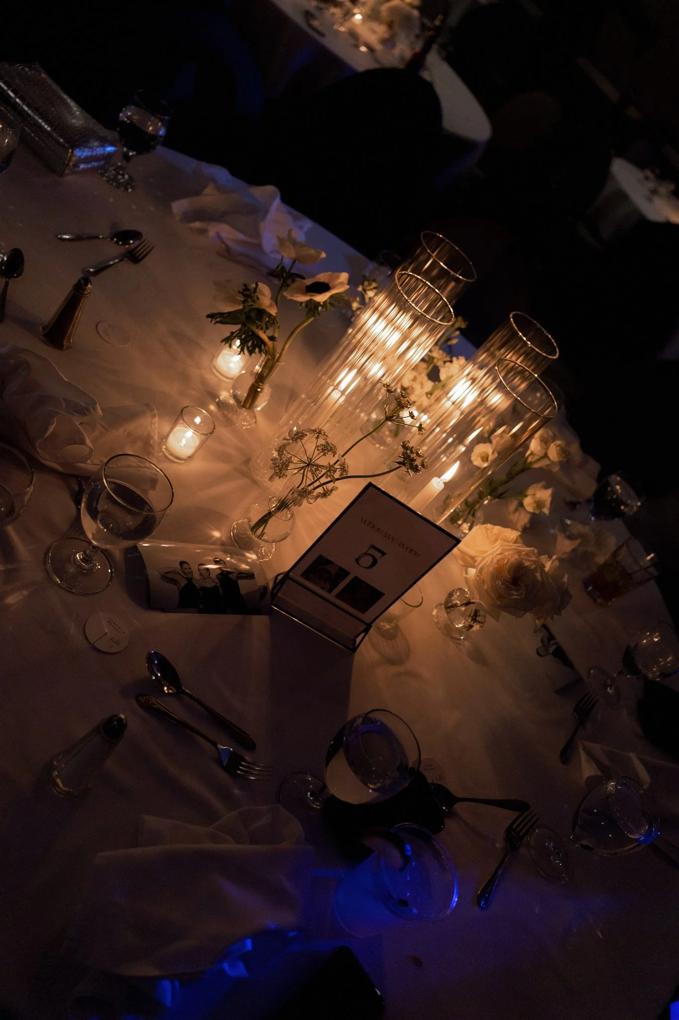 Evening reception illuminated by tall taper candles casting warm candlelight across white floral tables