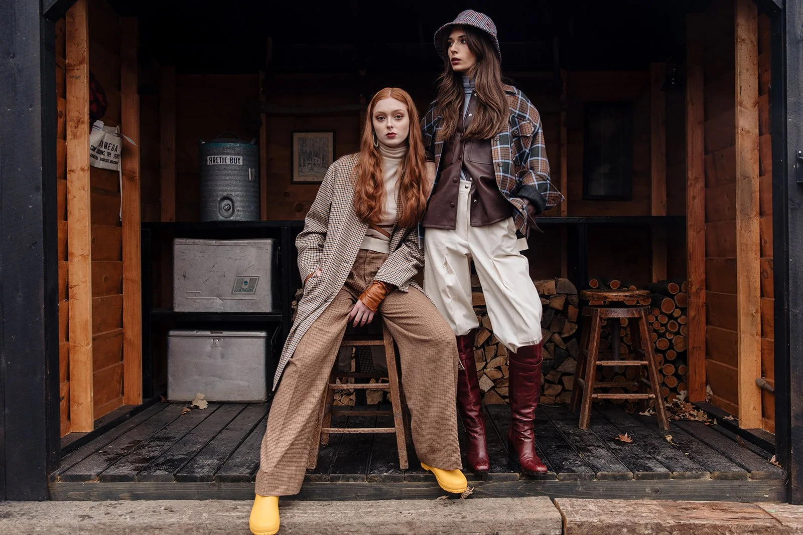 Fashion editorial two models in rustic cabin setting mixing plaid patterns earth tones lifestyle photography