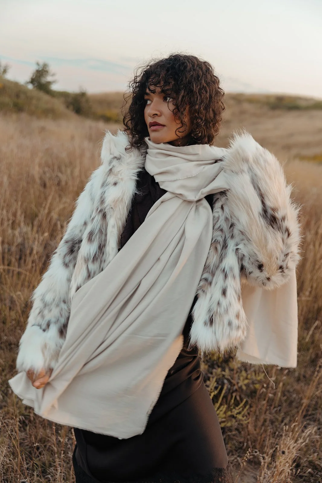 Lifestyle fashion photography woman in faux fur coat and ivory scarf golden hour prairie editorial by Chicago photographer Bekah Wriedt
